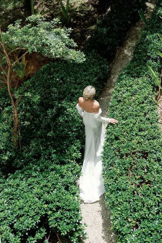 A woman in a white dress is standing in a garden.