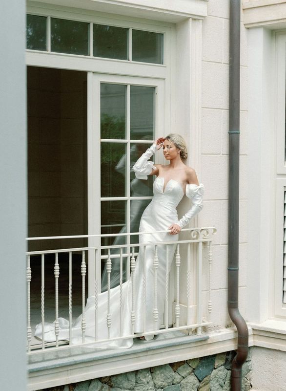 A woman in a wedding dress is standing on a balcony.