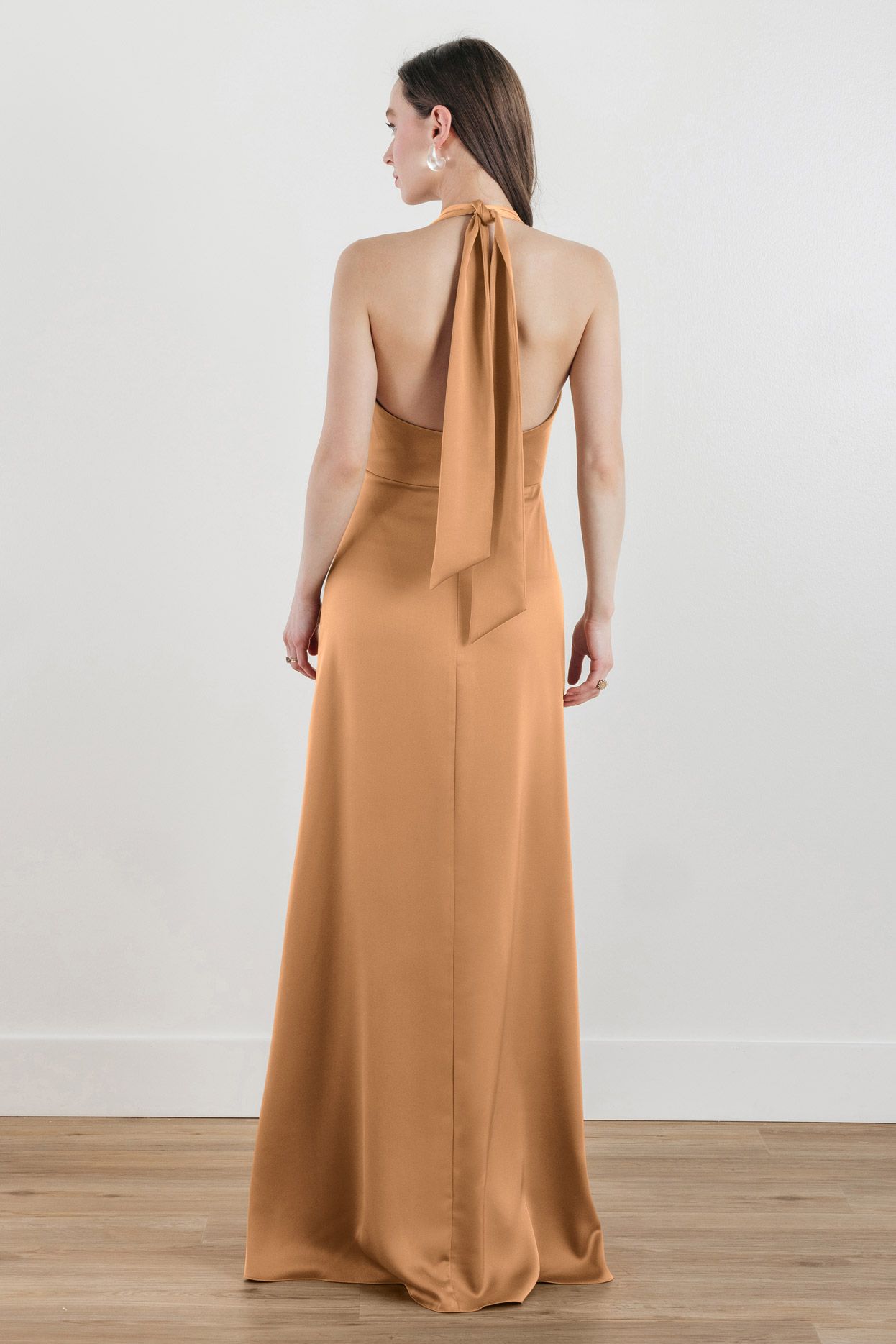 The back of a woman wearing a long brown dress with a halter neckline.