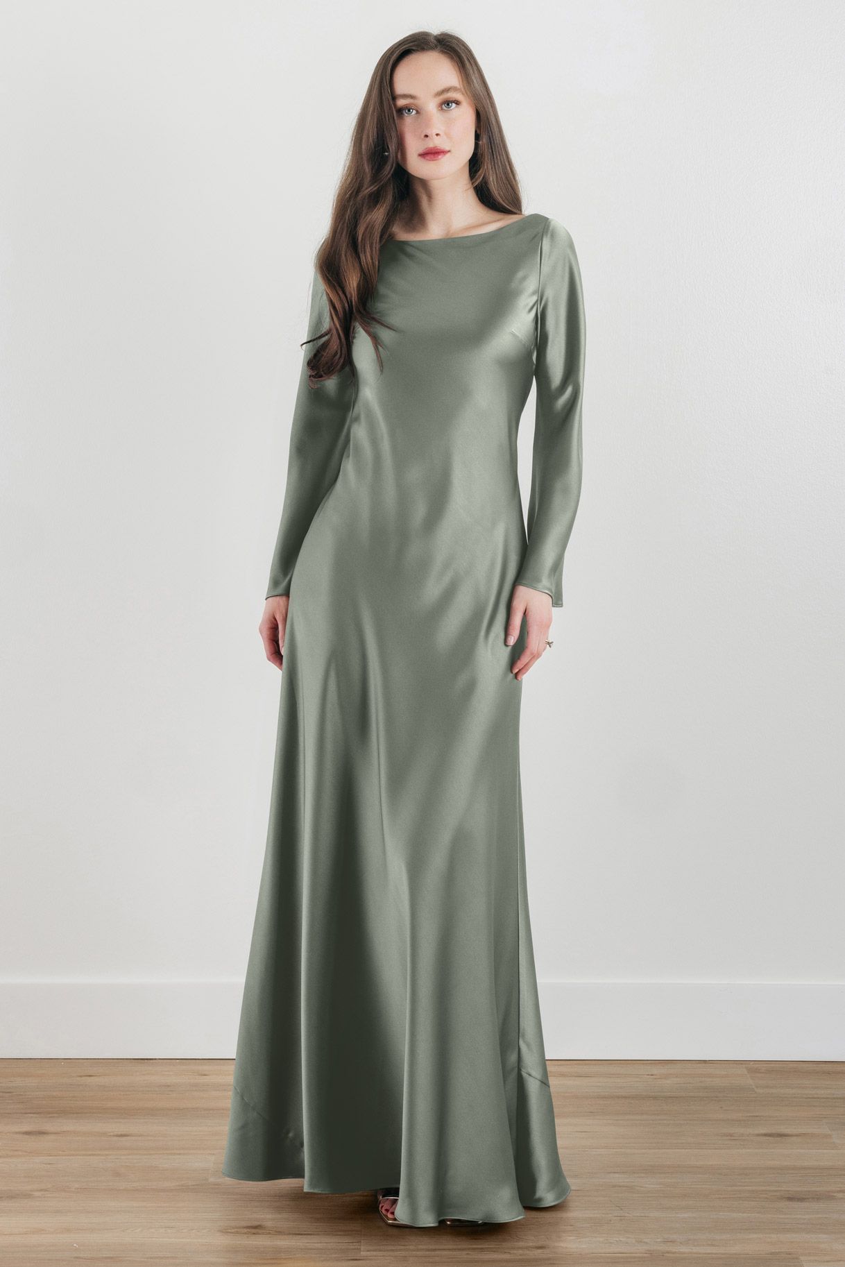 A woman is wearing a long satin dress with long sleeves.