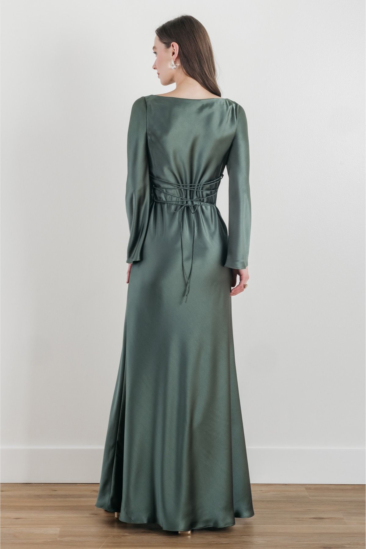 The back of a woman wearing a green satin dress with long sleeves.