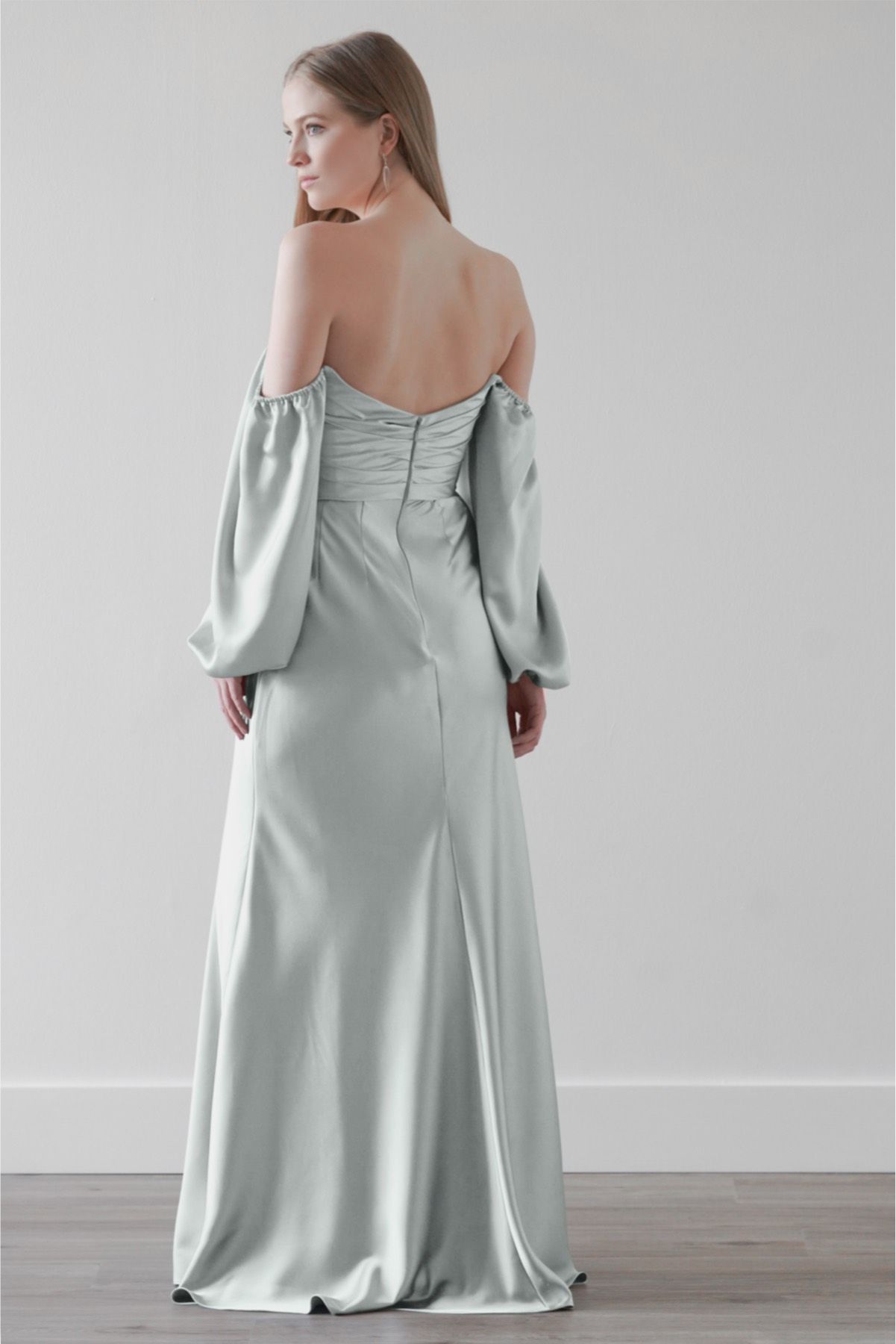 The back of a woman wearing a white off the shoulder dress with long sleeves.