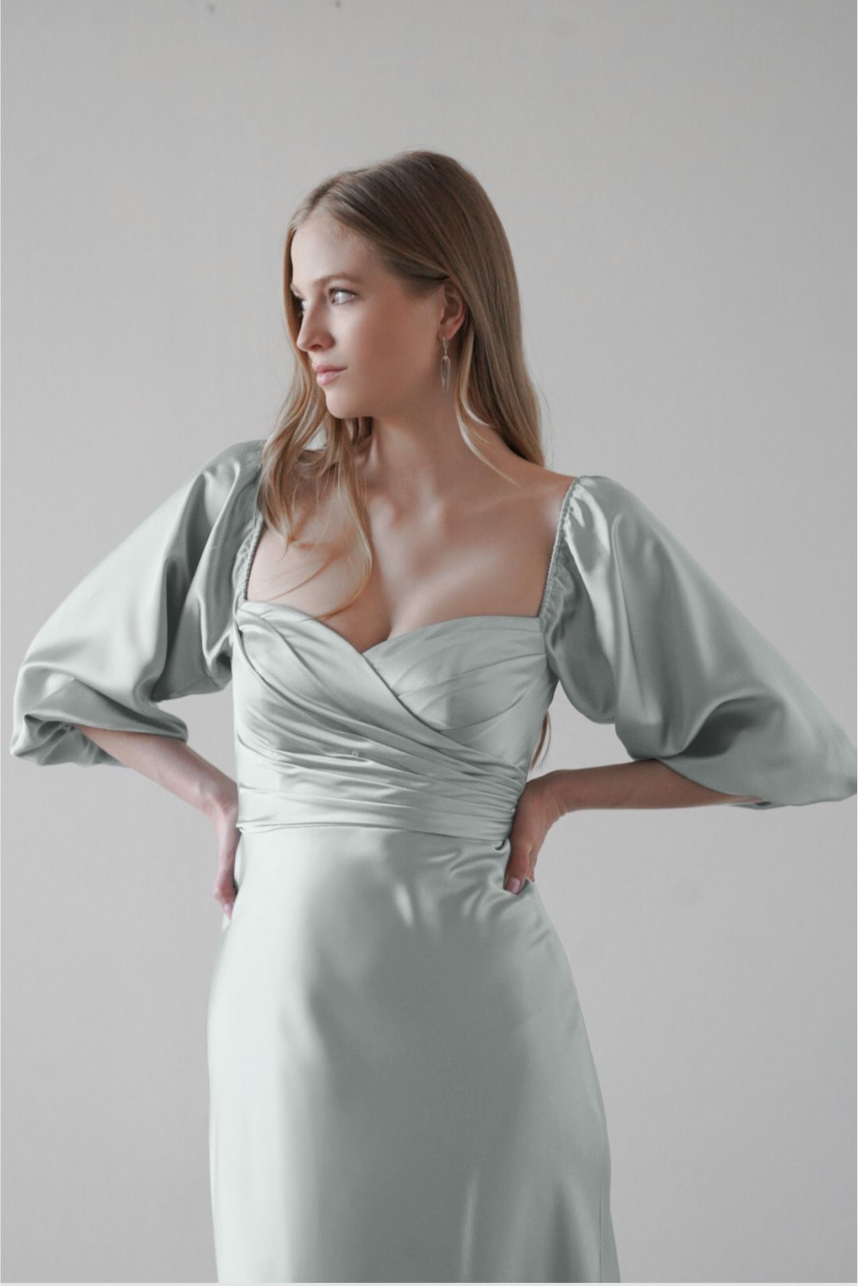 A woman is wearing a satin dress with puffed sleeves.