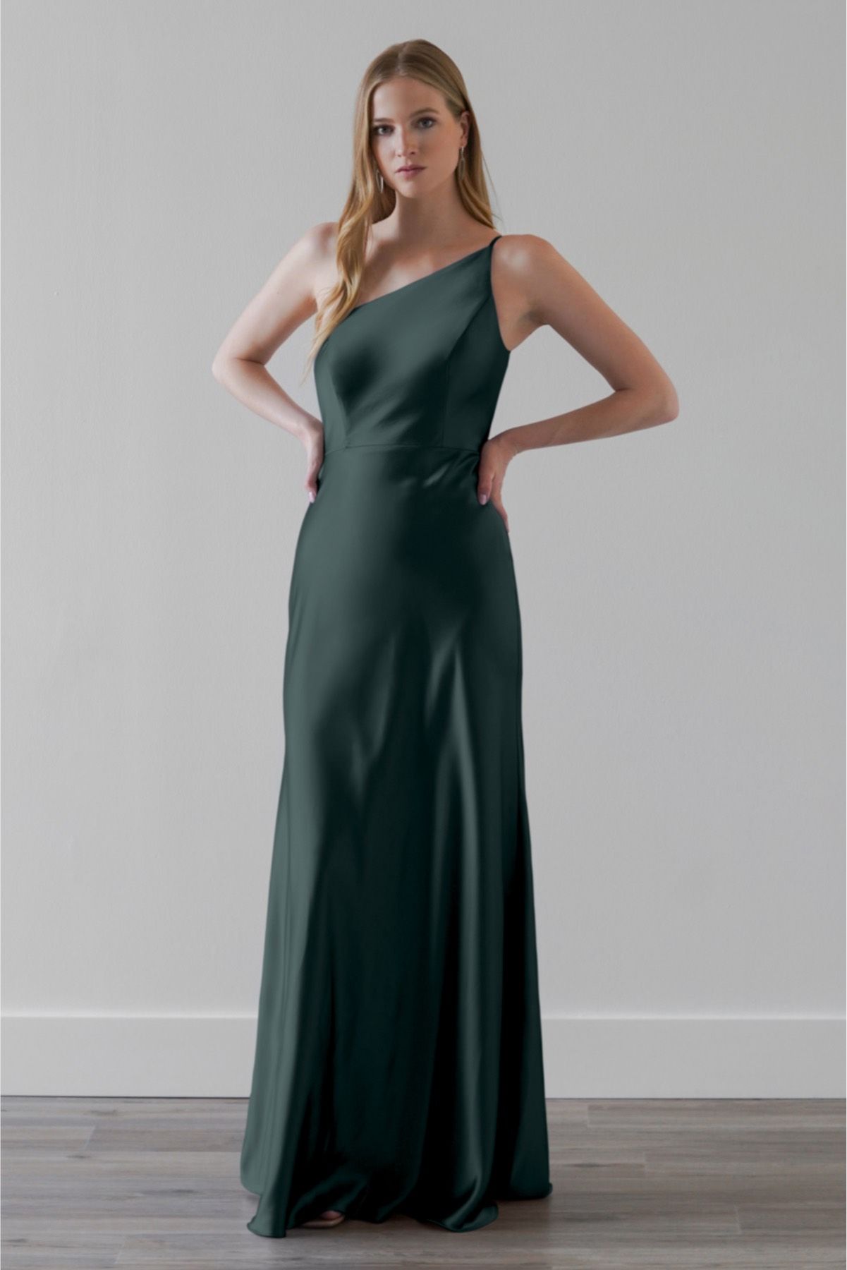 A woman is wearing a green one shoulder dress.