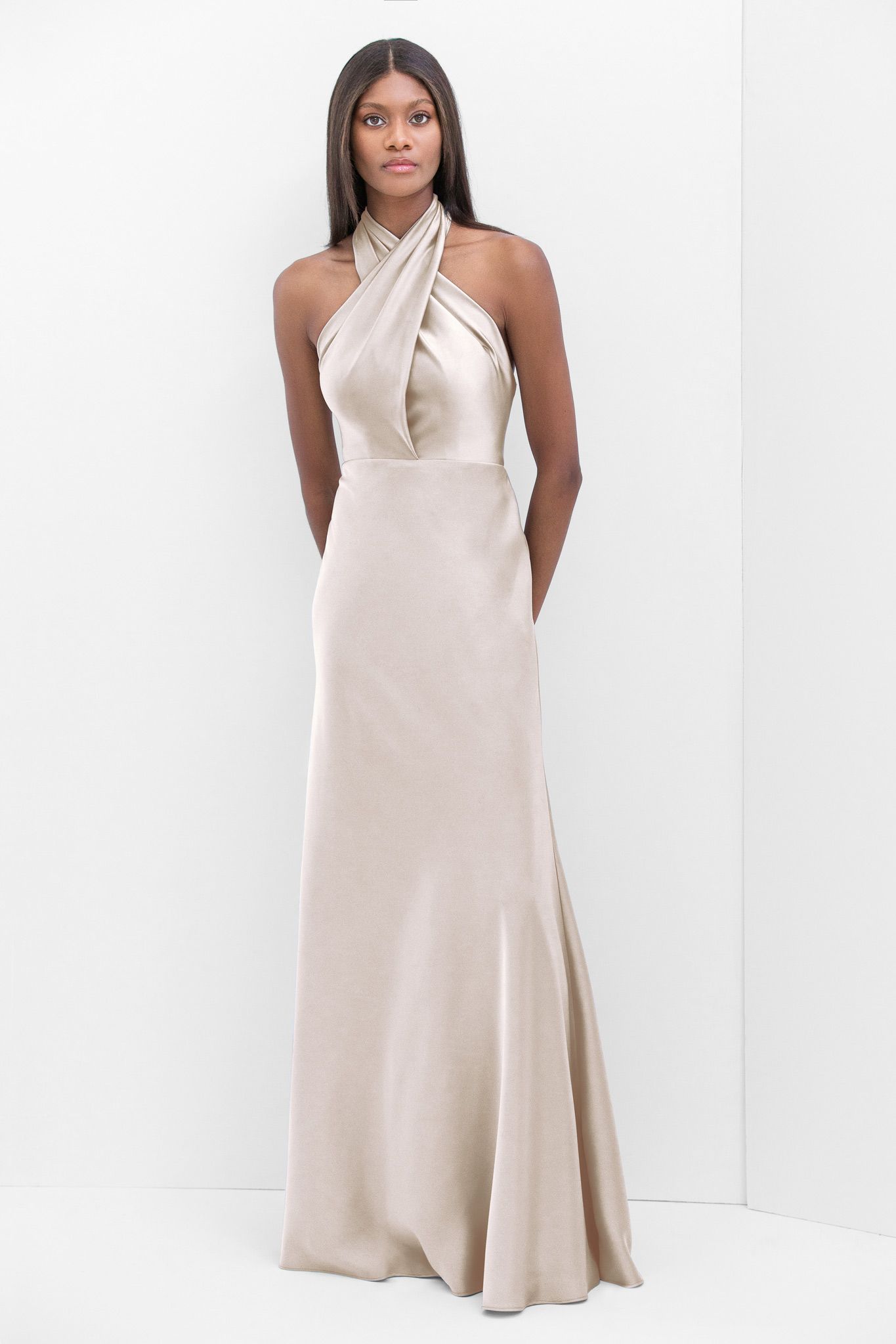 A woman is wearing a long white dress with a halter neckline.