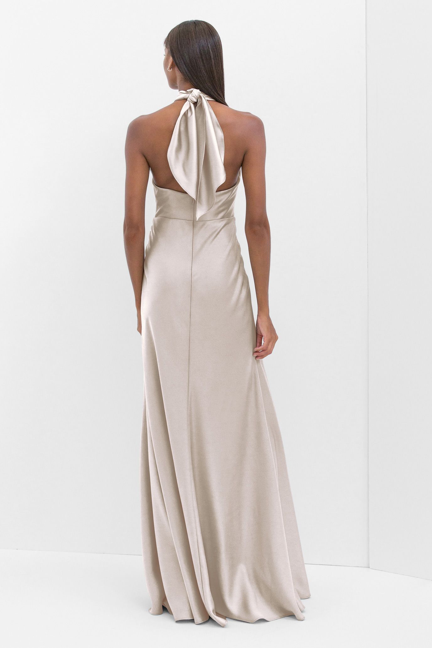 A woman is wearing a long white dress with a halter neckline.