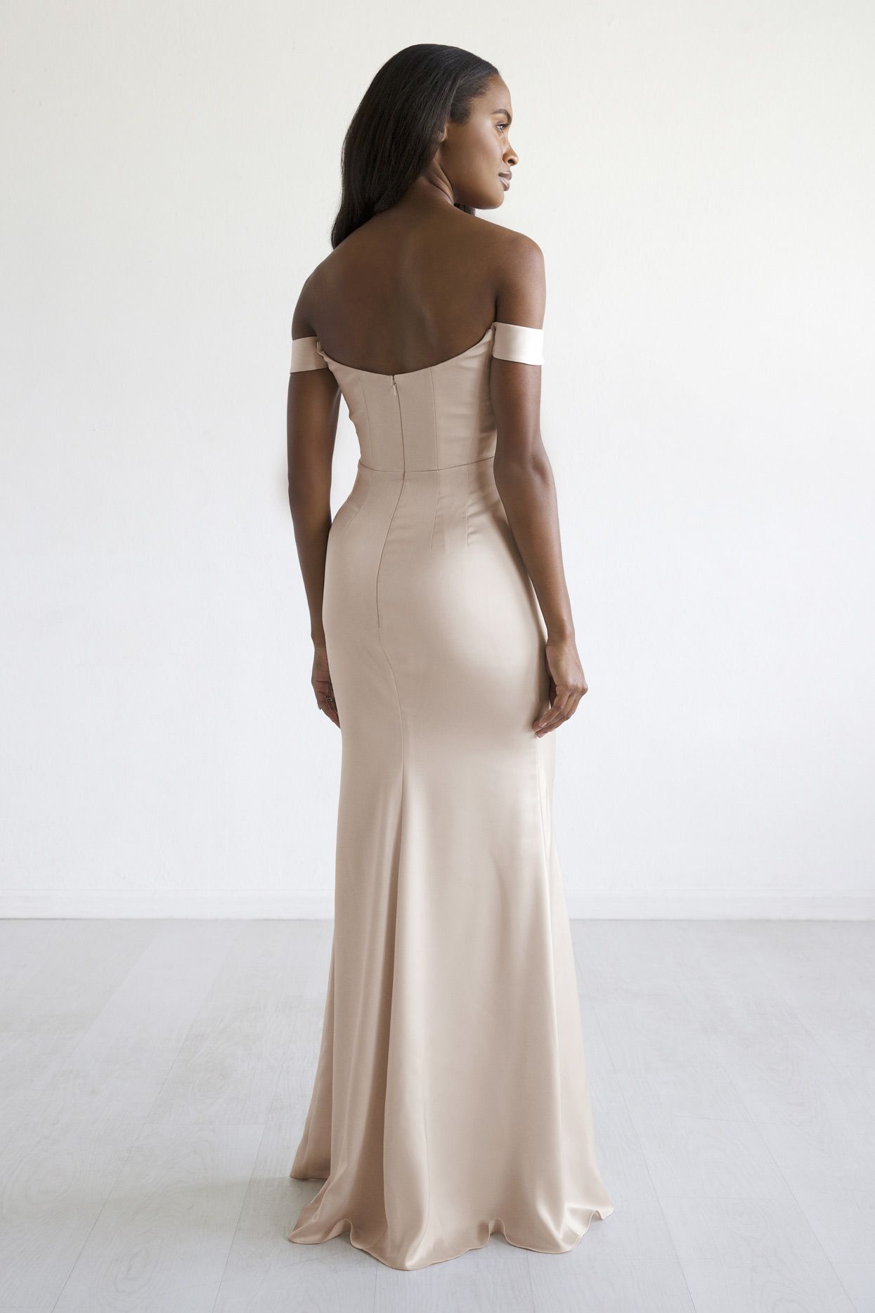 The back of a woman wearing a beige off the shoulder dress.