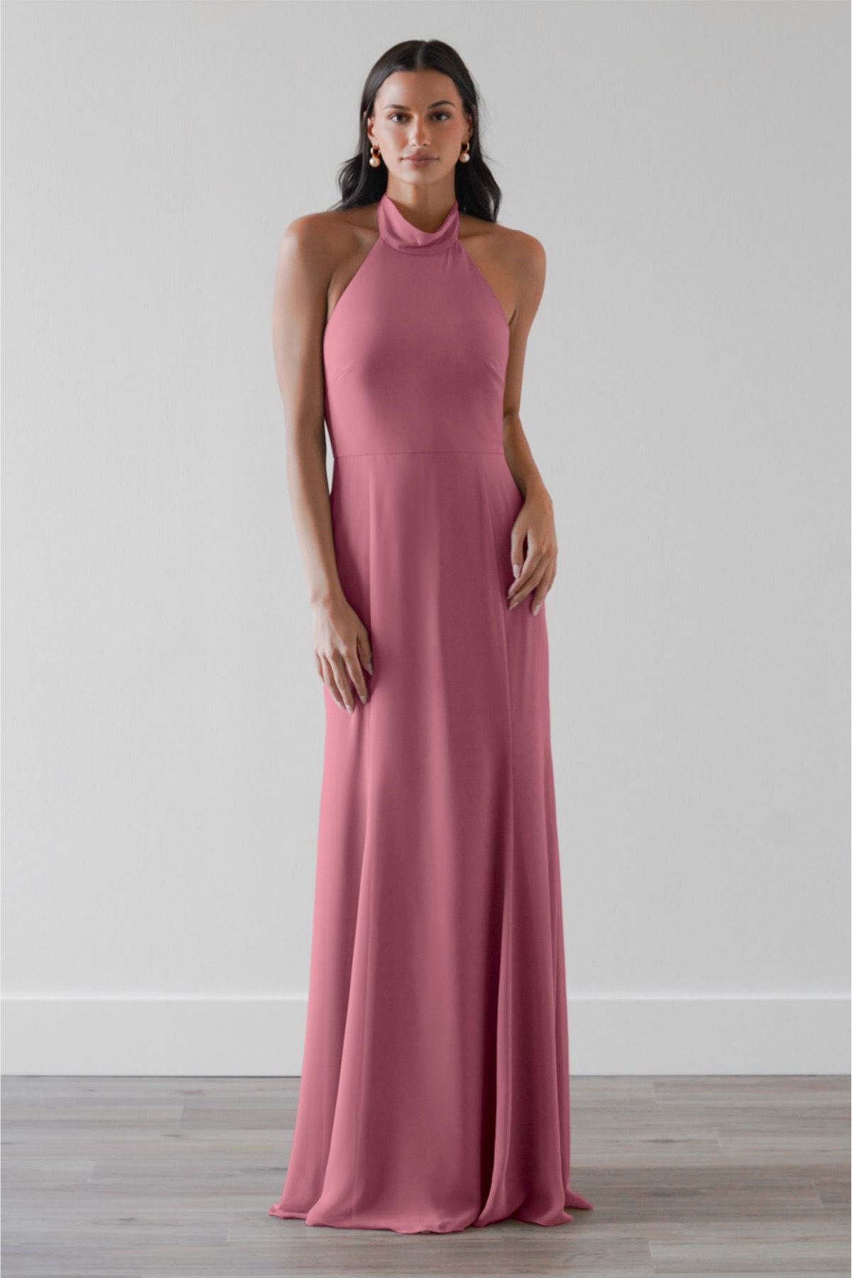 A woman is wearing a pink bridesmaid dress with a halter neckline.