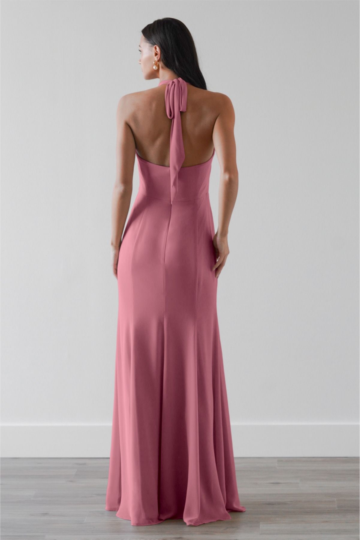The back of a woman wearing a pink dress with a halter neckline.