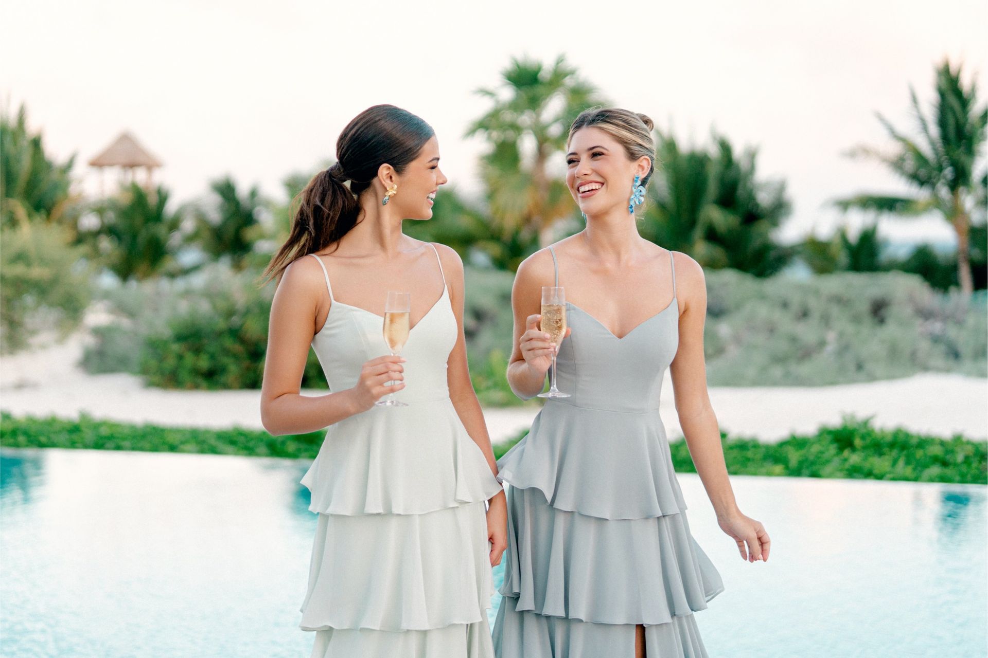 Two women in dresses are standing next to each other holding champagne glasses.