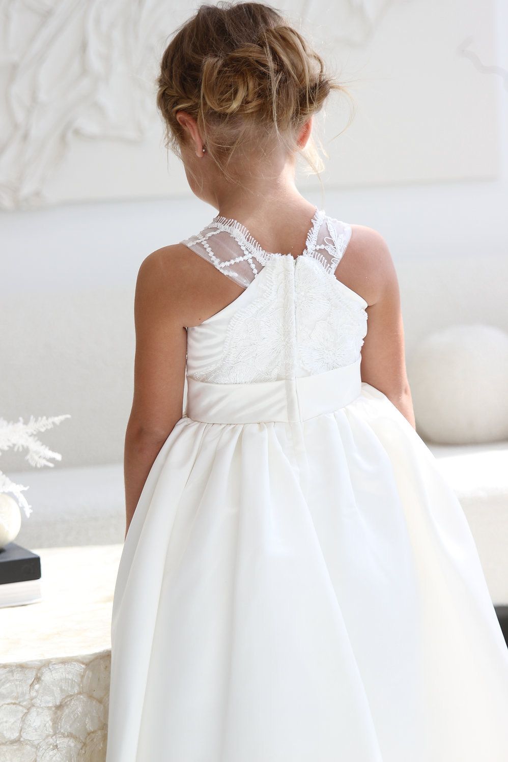 A little girl is wearing a white flower girl dress.