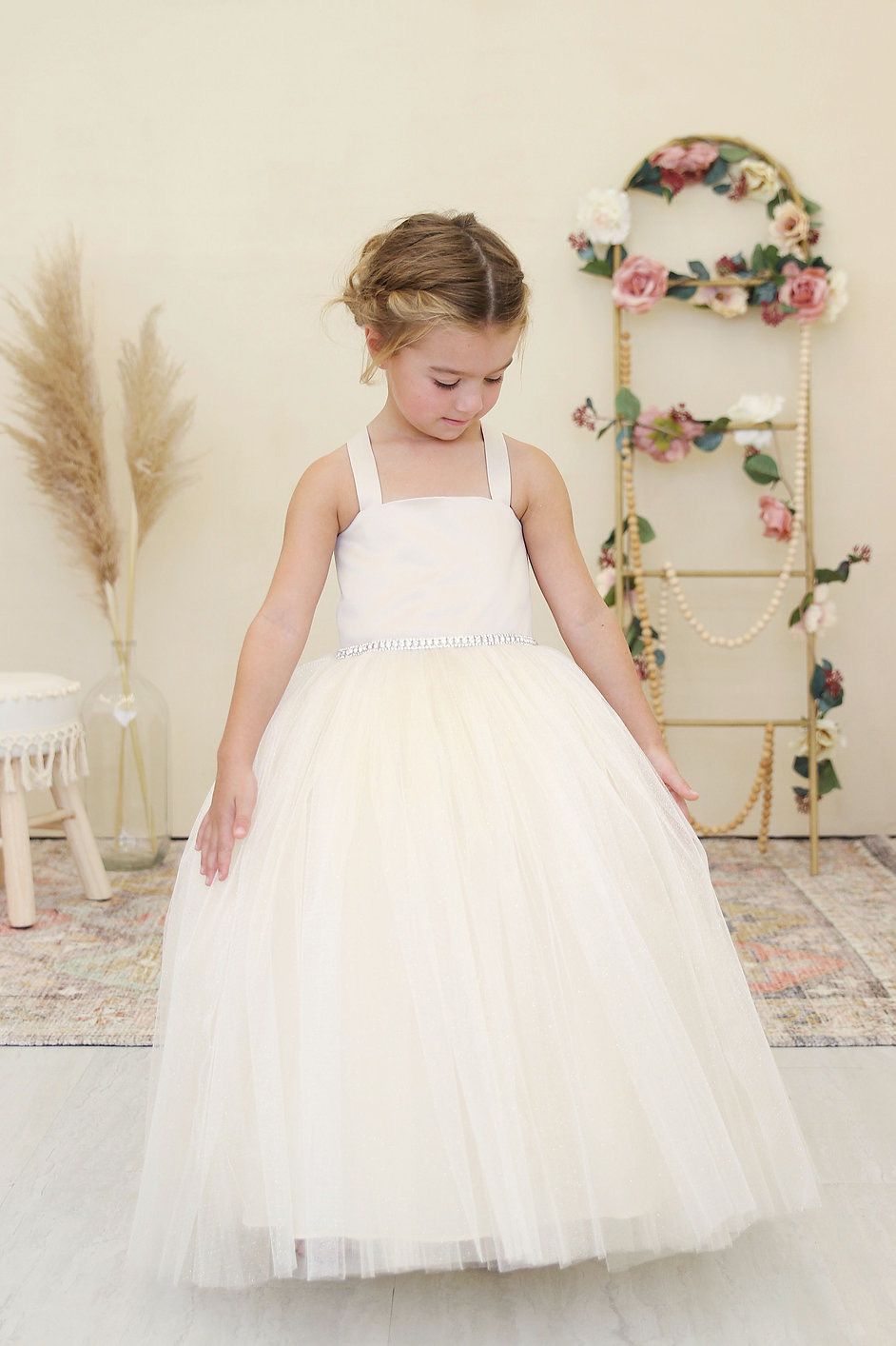A little girl is wearing a white flower girl dress.