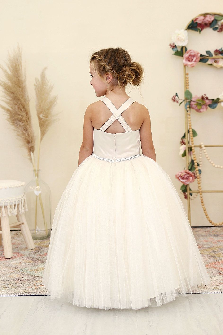 A little girl is wearing a white flower girl dress.