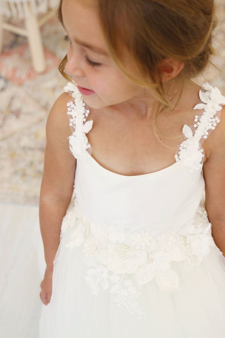 A little girl is wearing a white flower girl dress.
