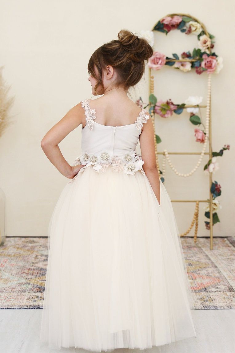 A little girl is wearing a white flower girl dress.