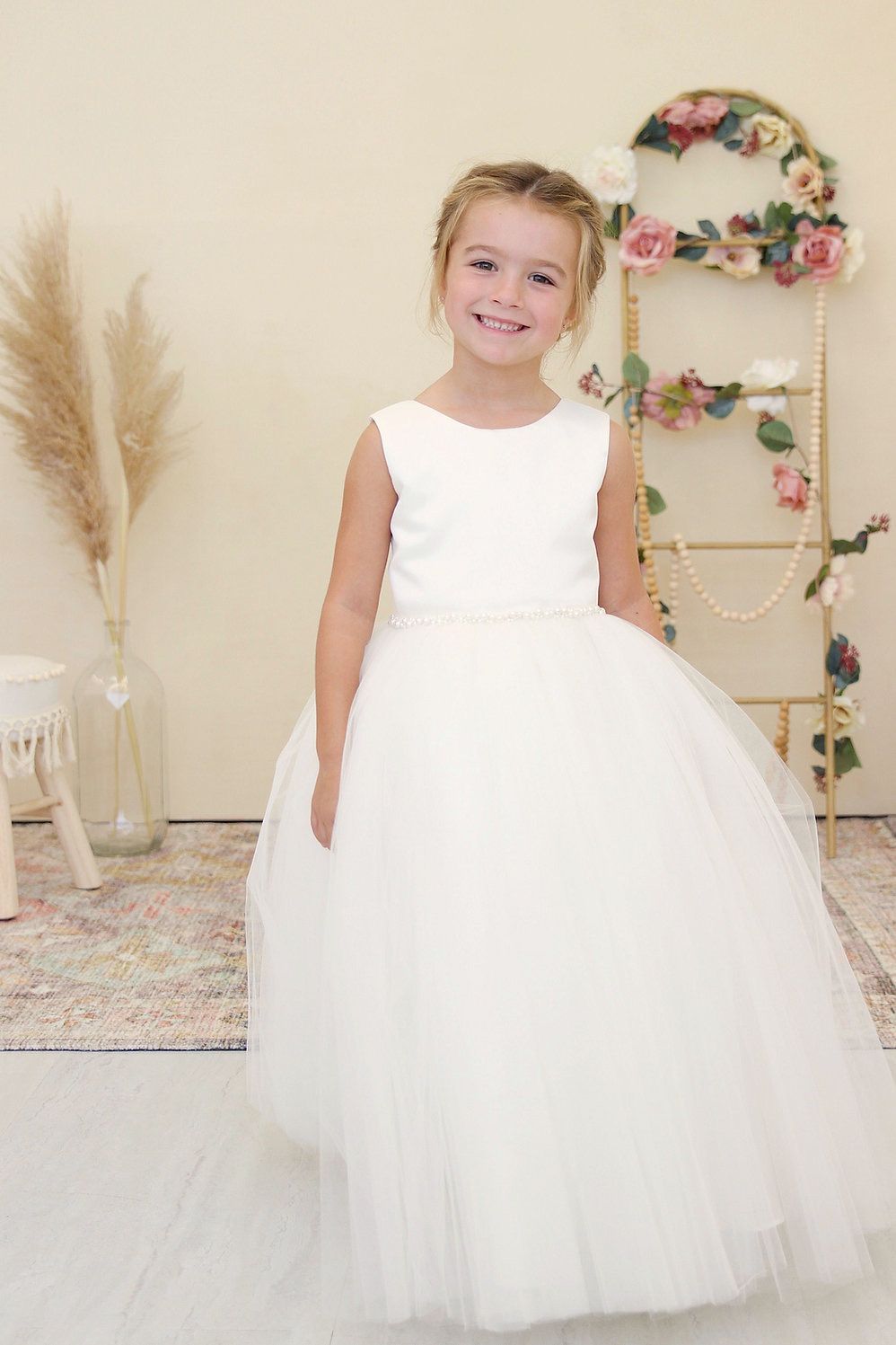 A little girl is wearing a white flower girl dress.