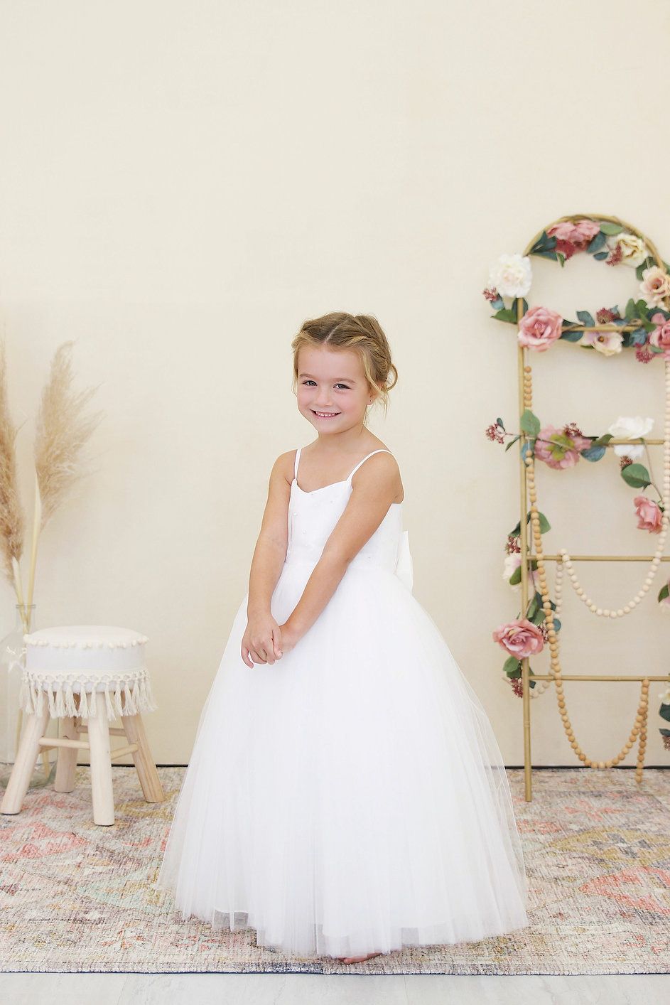 A little girl in a white dress is standing in a room.