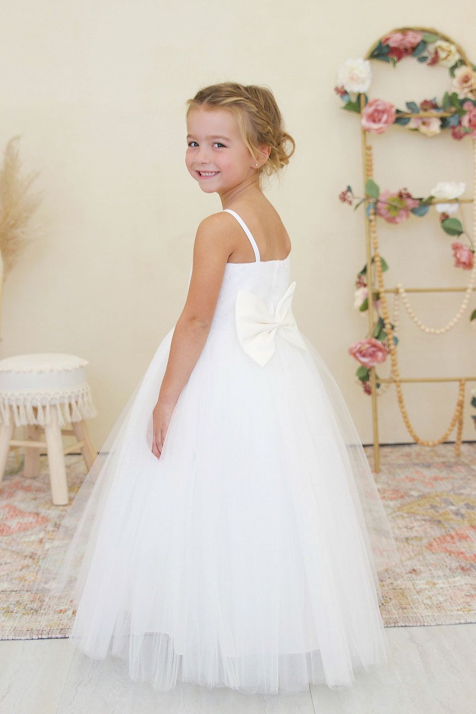 A little girl is wearing a white flower girl dress.