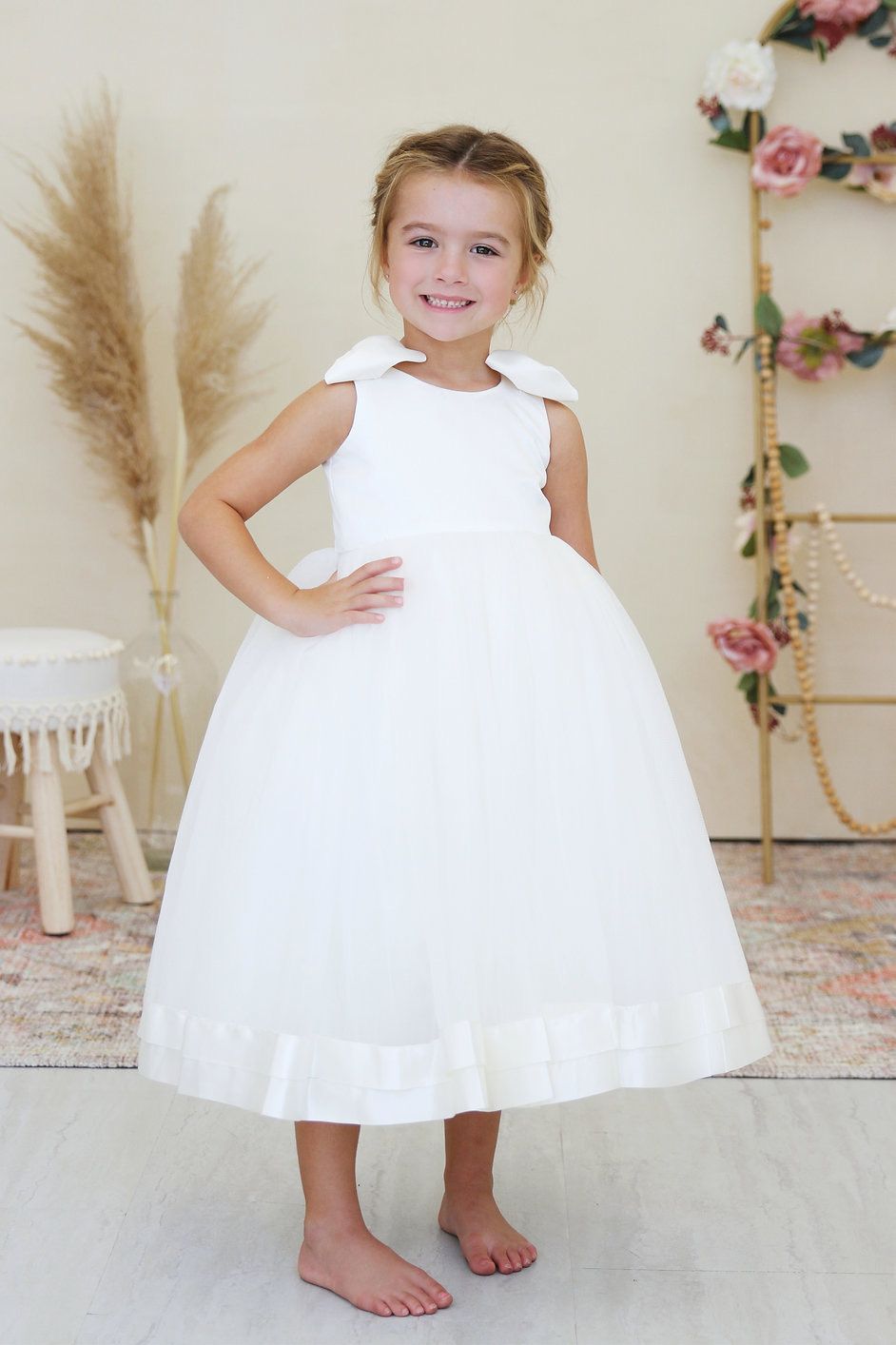 A little girl is wearing a white flower girl dress.