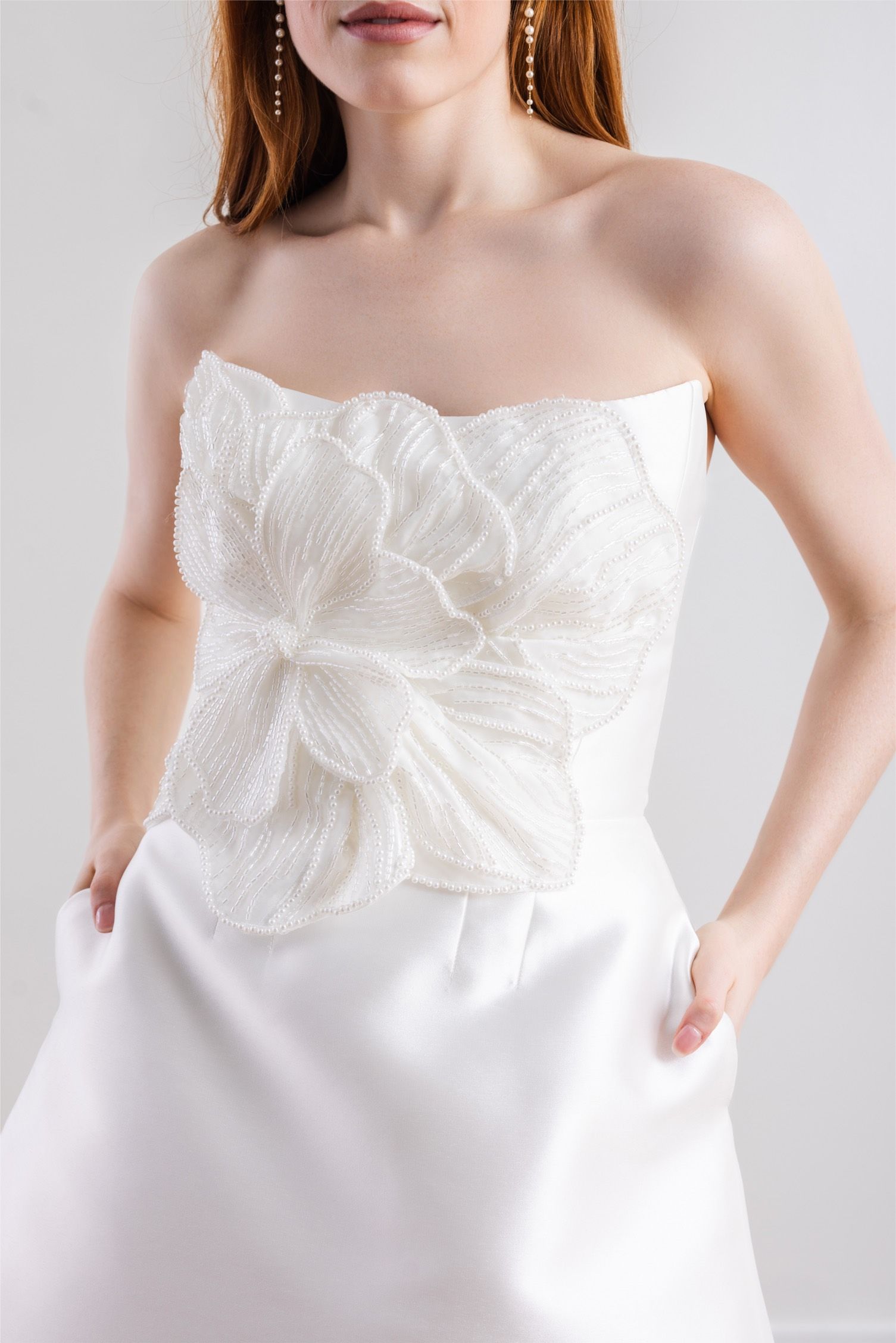 A woman is wearing a white strapless dress with a bow on the top.