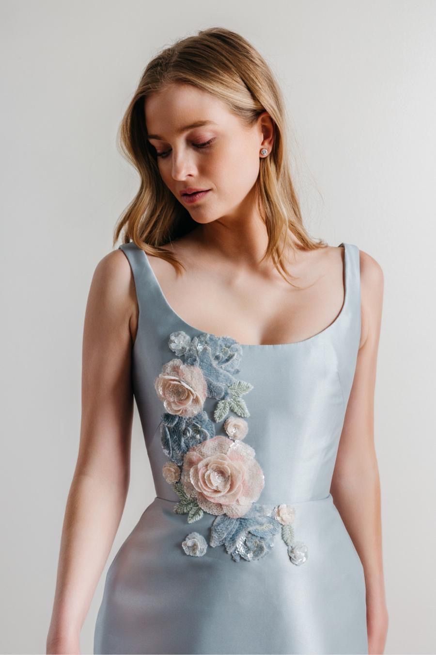 A woman is wearing a light blue dress with flowers on it.