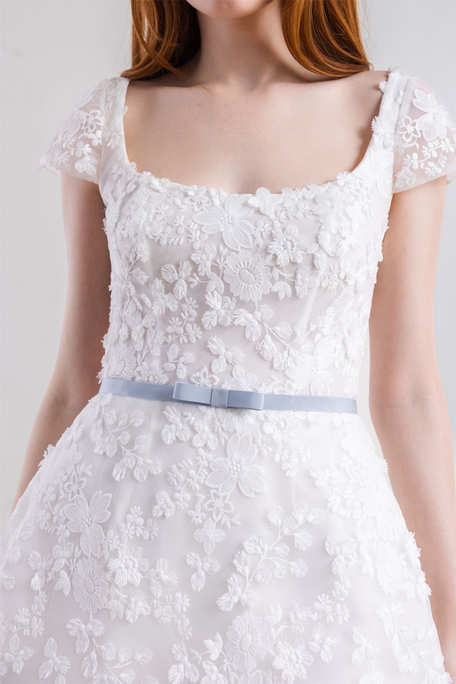 A woman is wearing a white wedding dress with a blue belt.