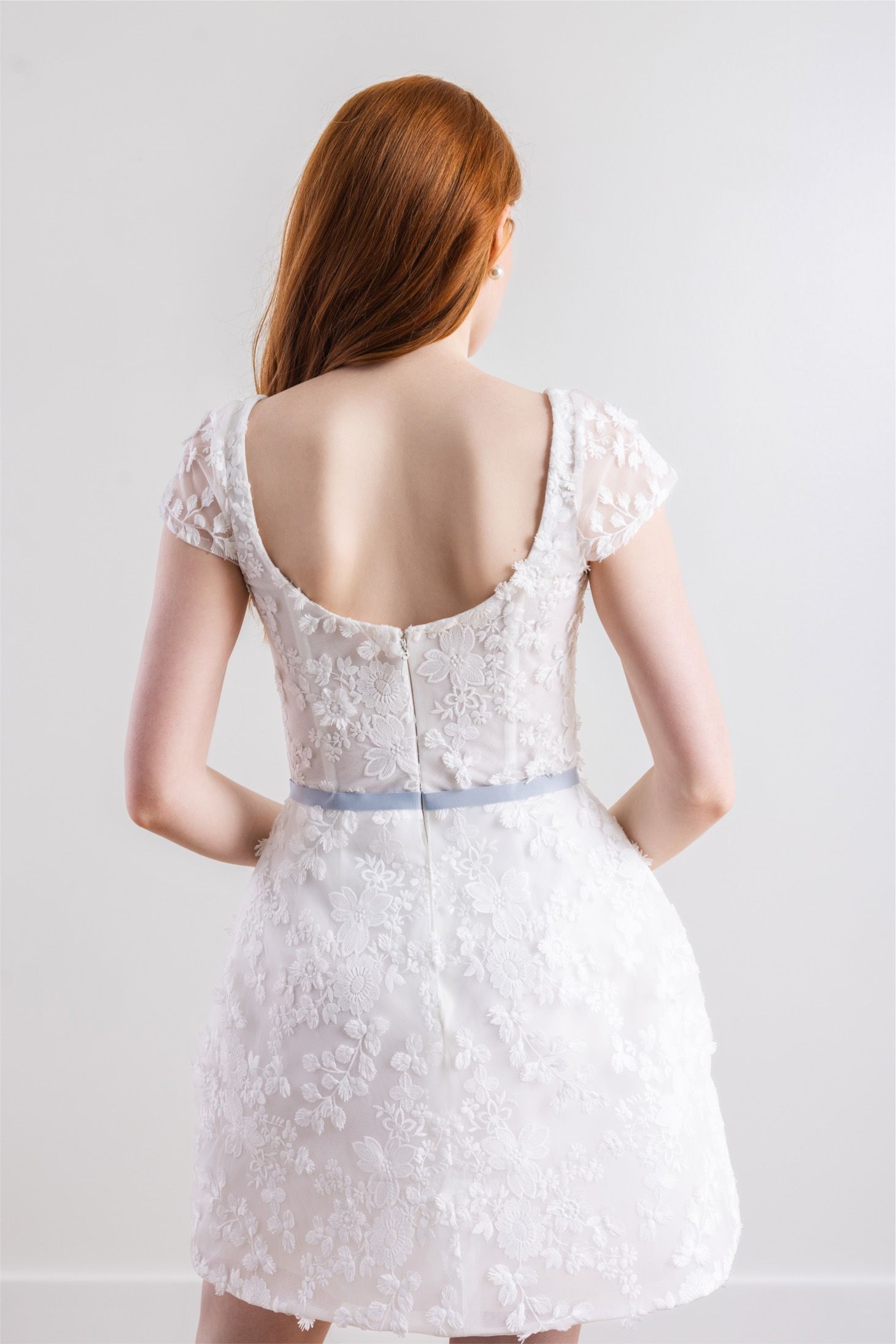 The back of a woman wearing a white lace dress.