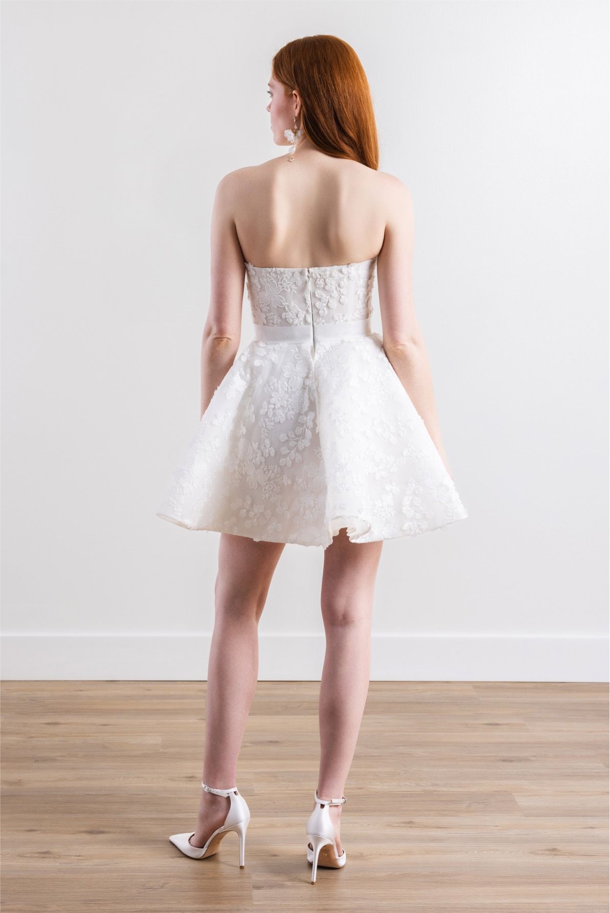 The back of a woman wearing a white dress and heels.