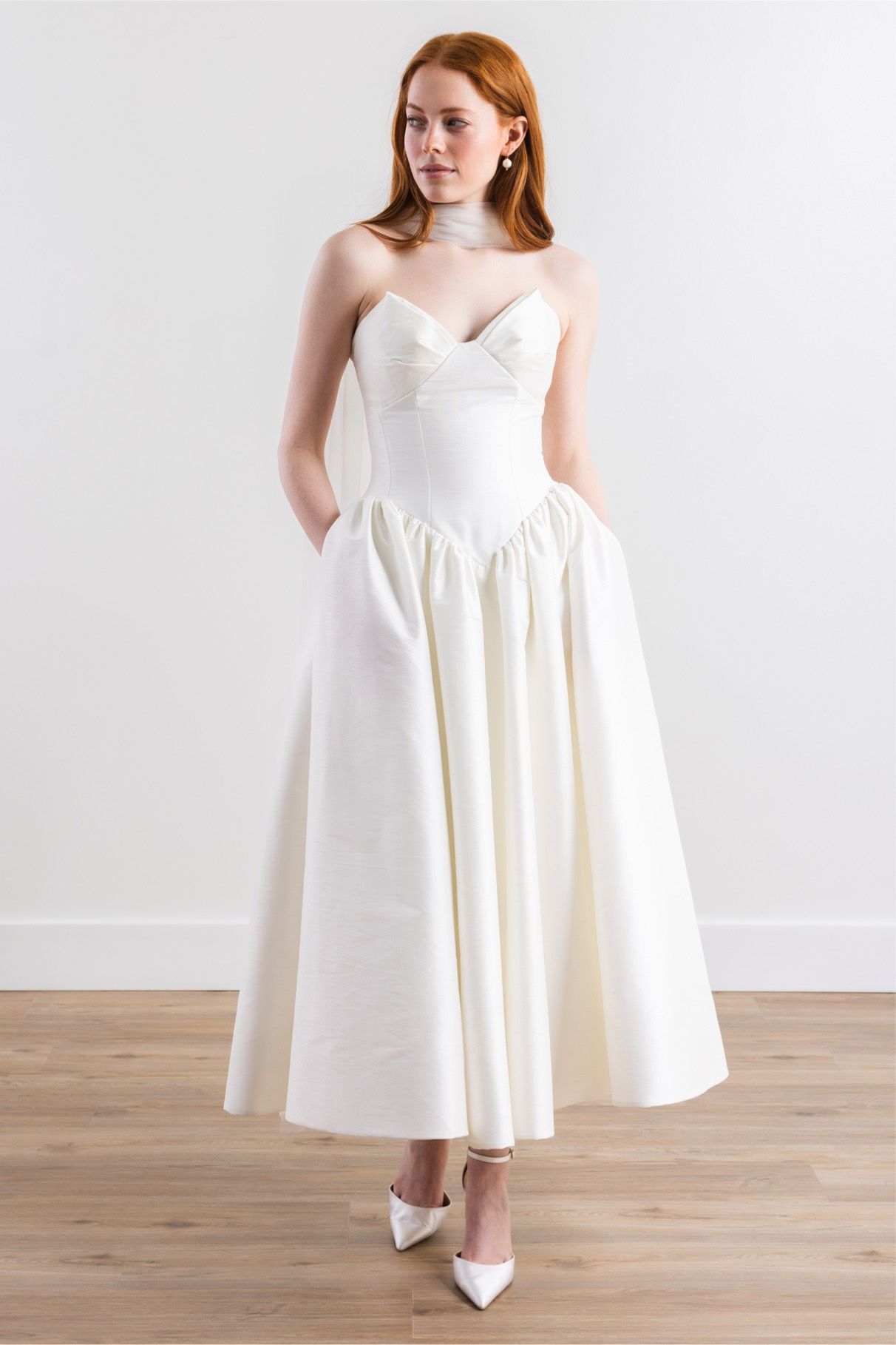 A woman is wearing a white wedding dress and white shoes.