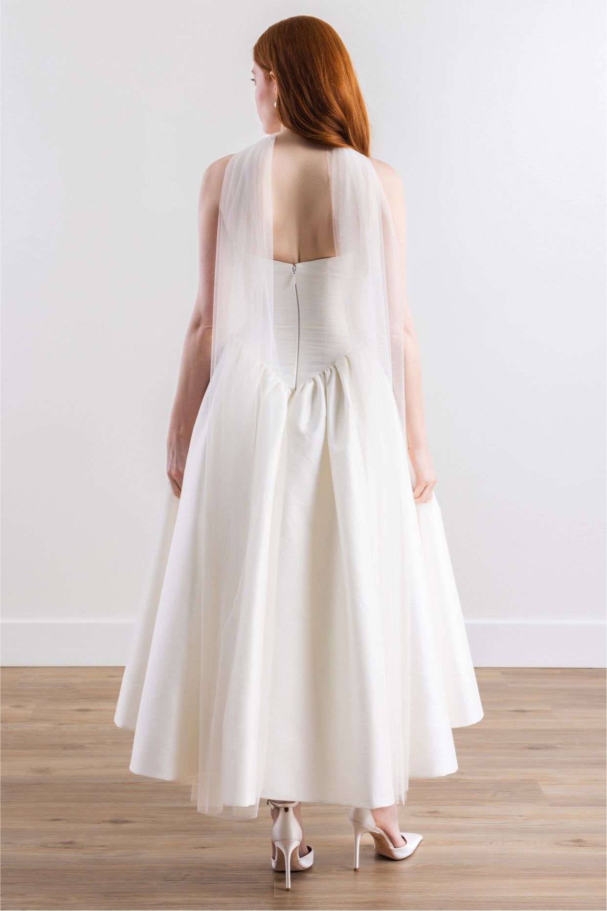 The back of a woman wearing a white wedding dress and heels.