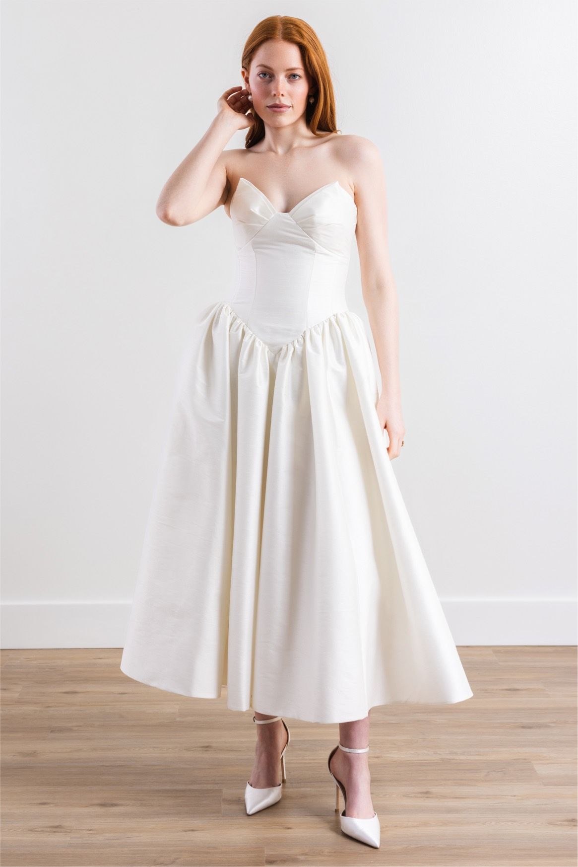 A woman is wearing a white wedding dress and white heels.