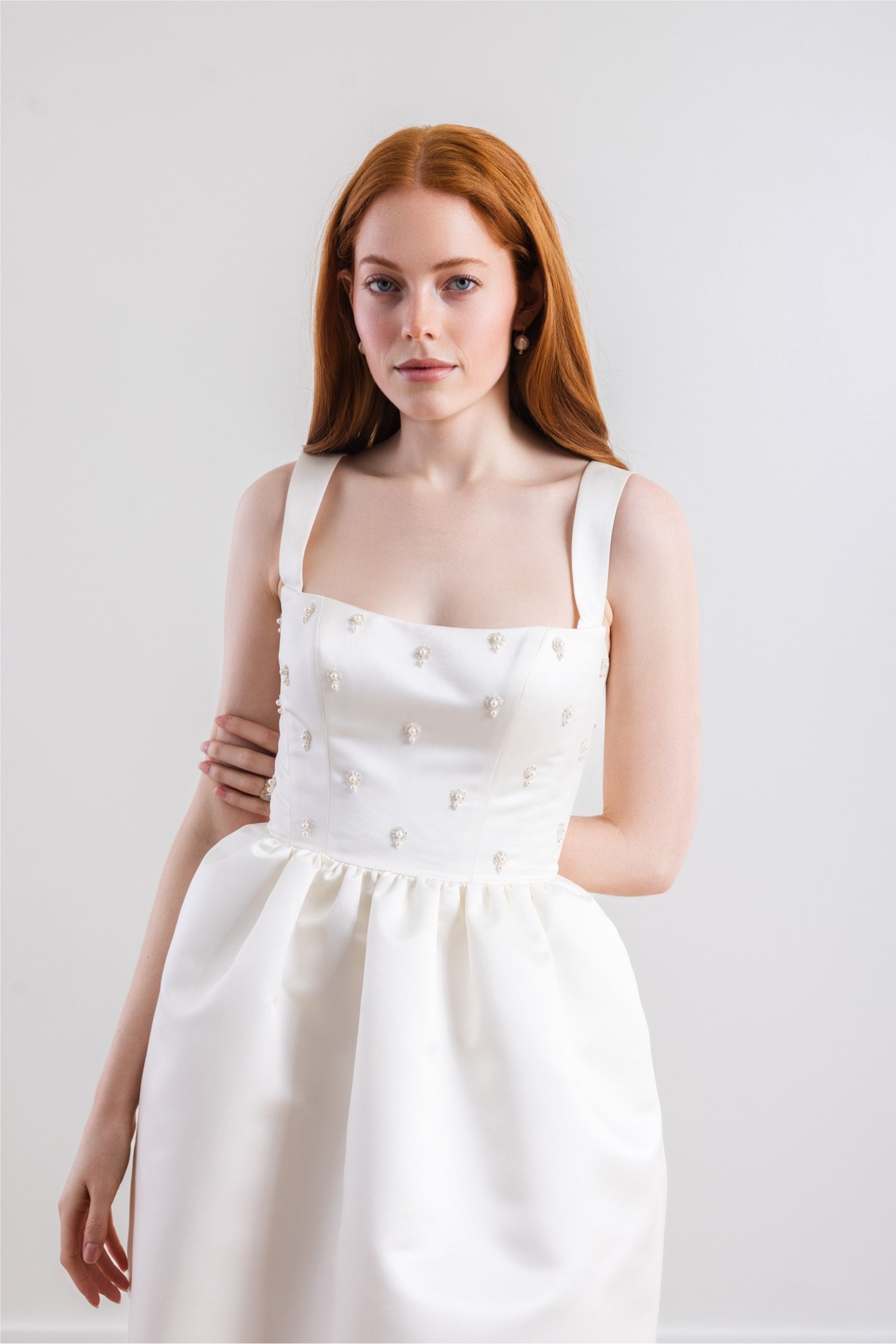 A woman is wearing a white dress with pearls on it.