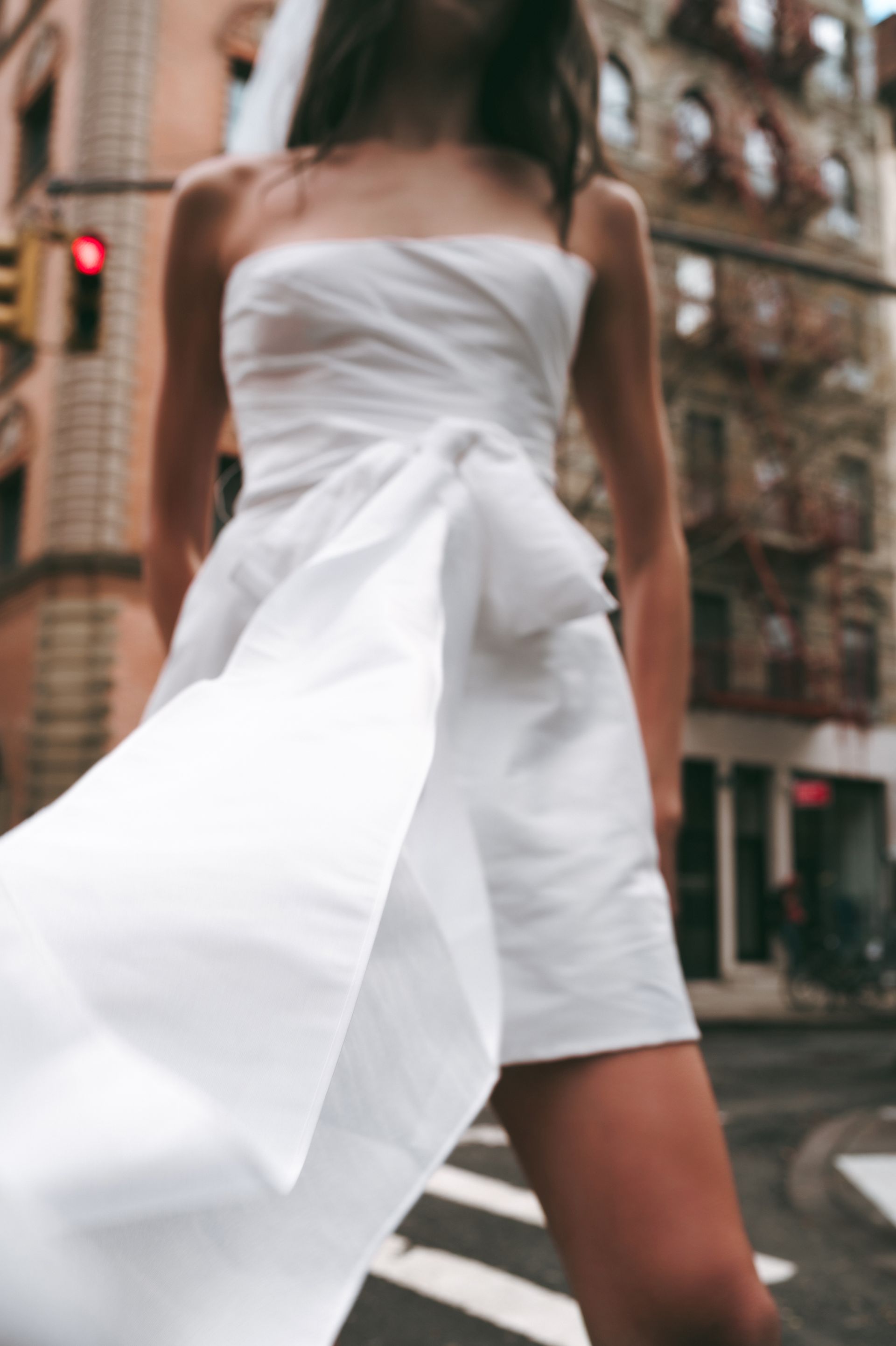 A woman in a white dress and veil is walking down the street.