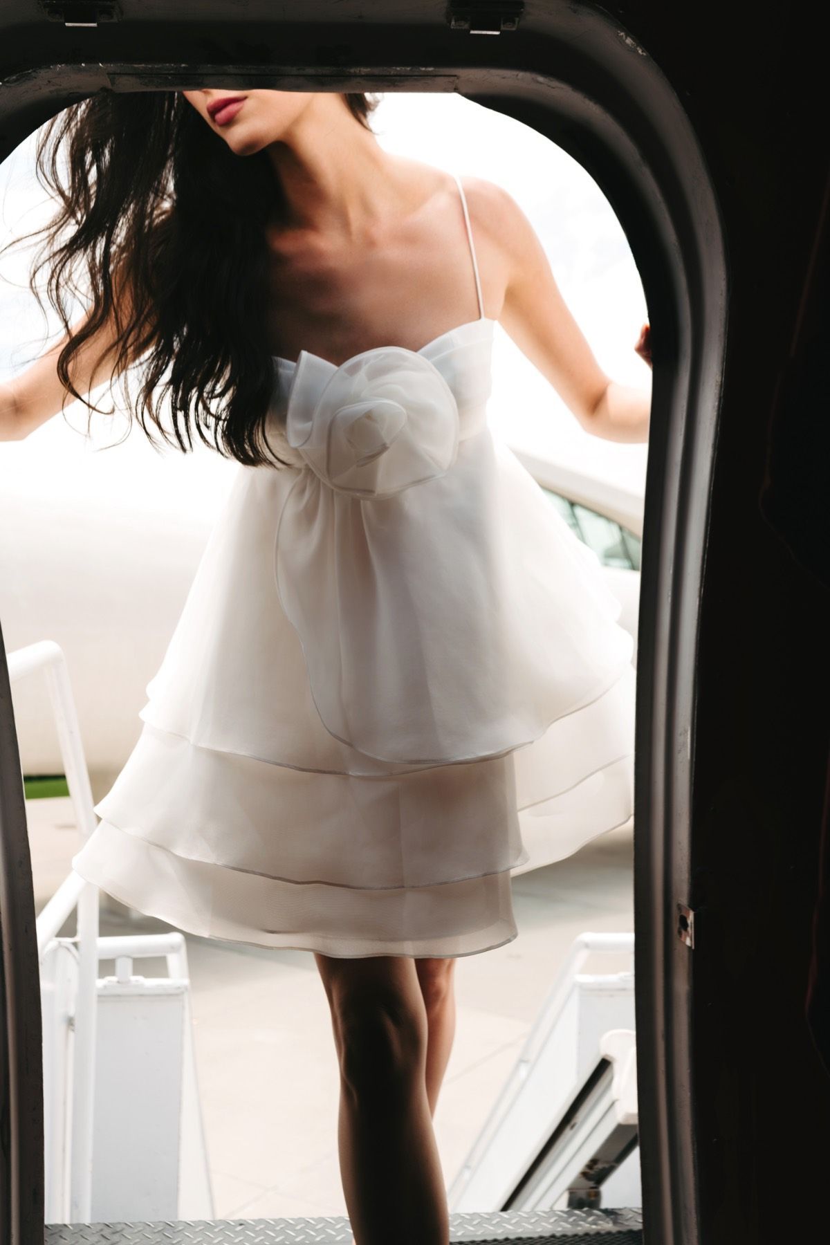 A woman in a white dress is standing in a doorway
