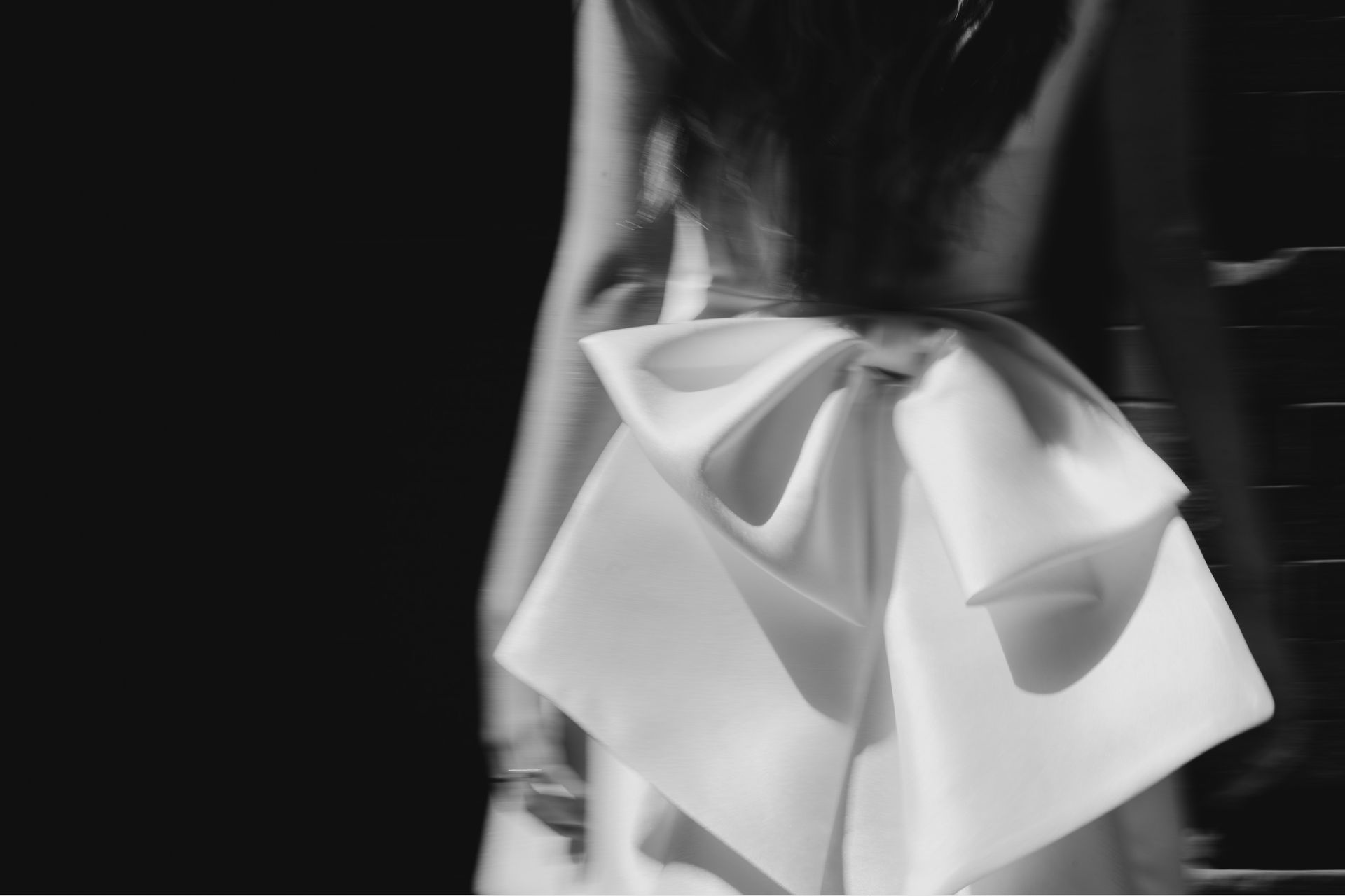 A woman is wearing a white dress with a bow on the back.