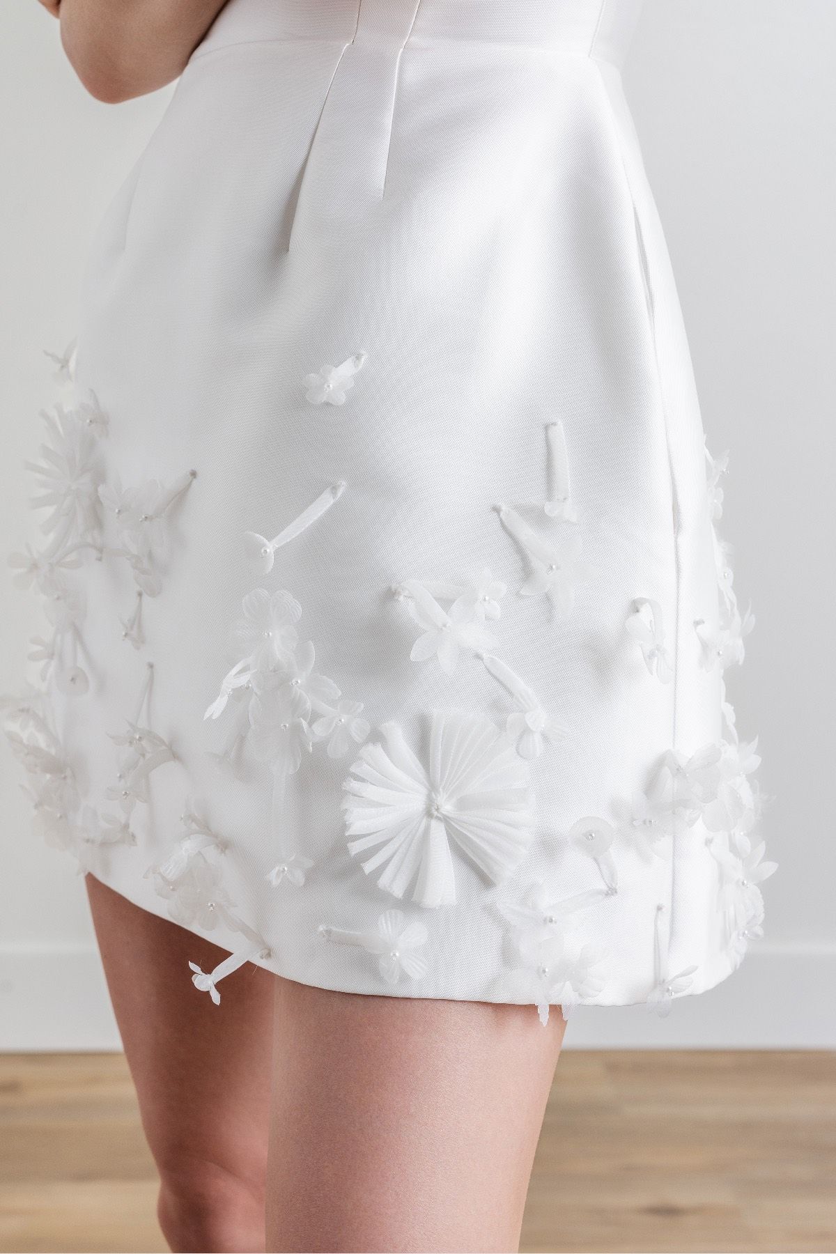 A woman is wearing a white skirt with flowers on it.