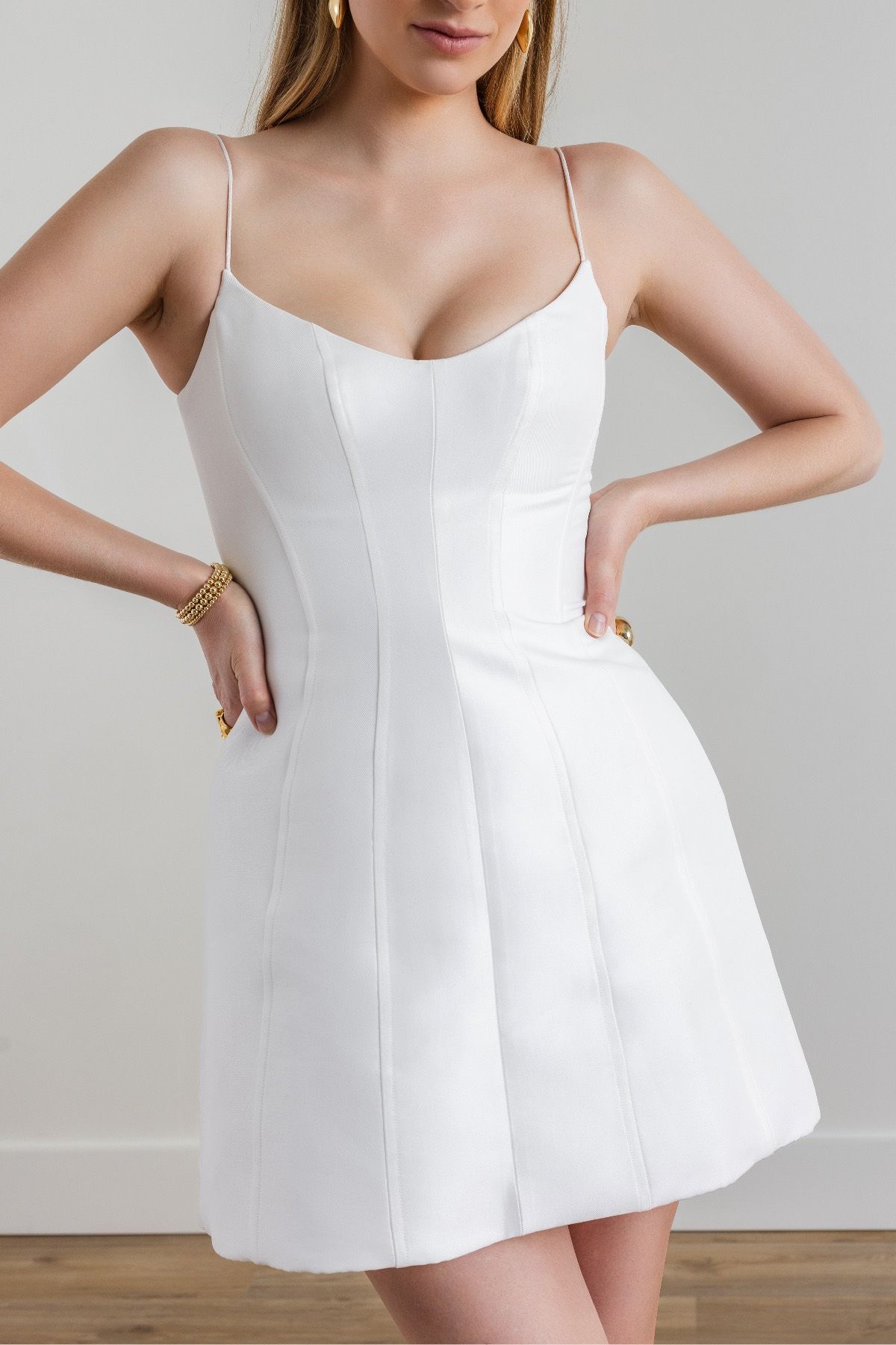 A woman is wearing a white dress with spaghetti straps.