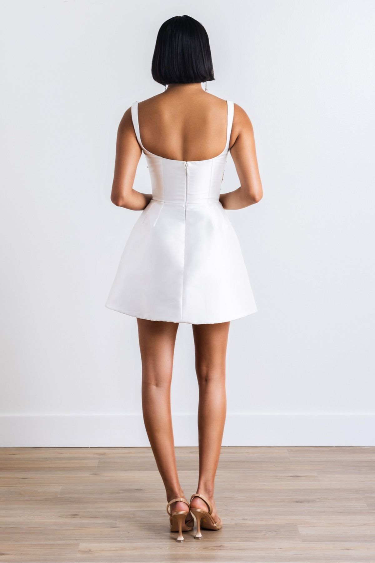 The back of a woman wearing a white dress and heels.