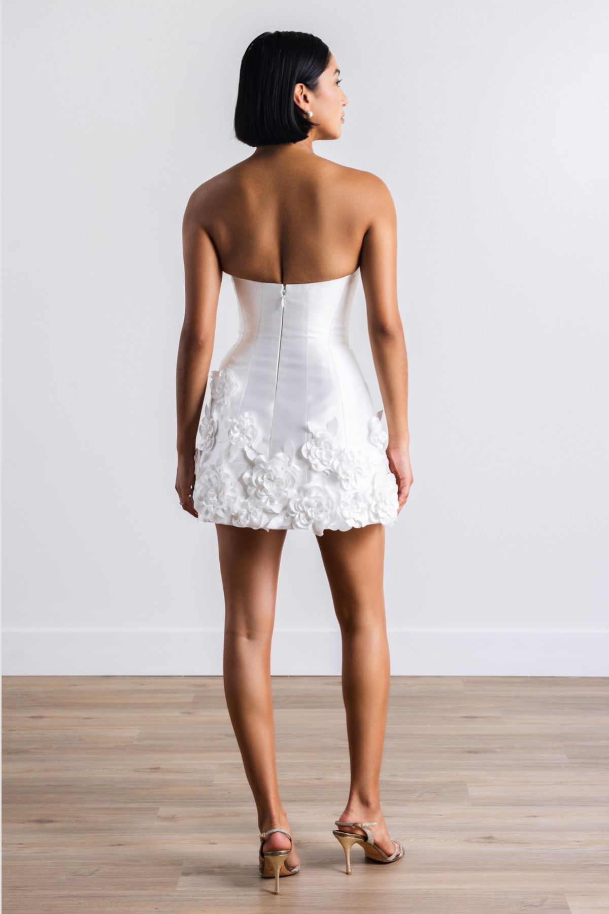 The back of a woman wearing a white dress and heels.