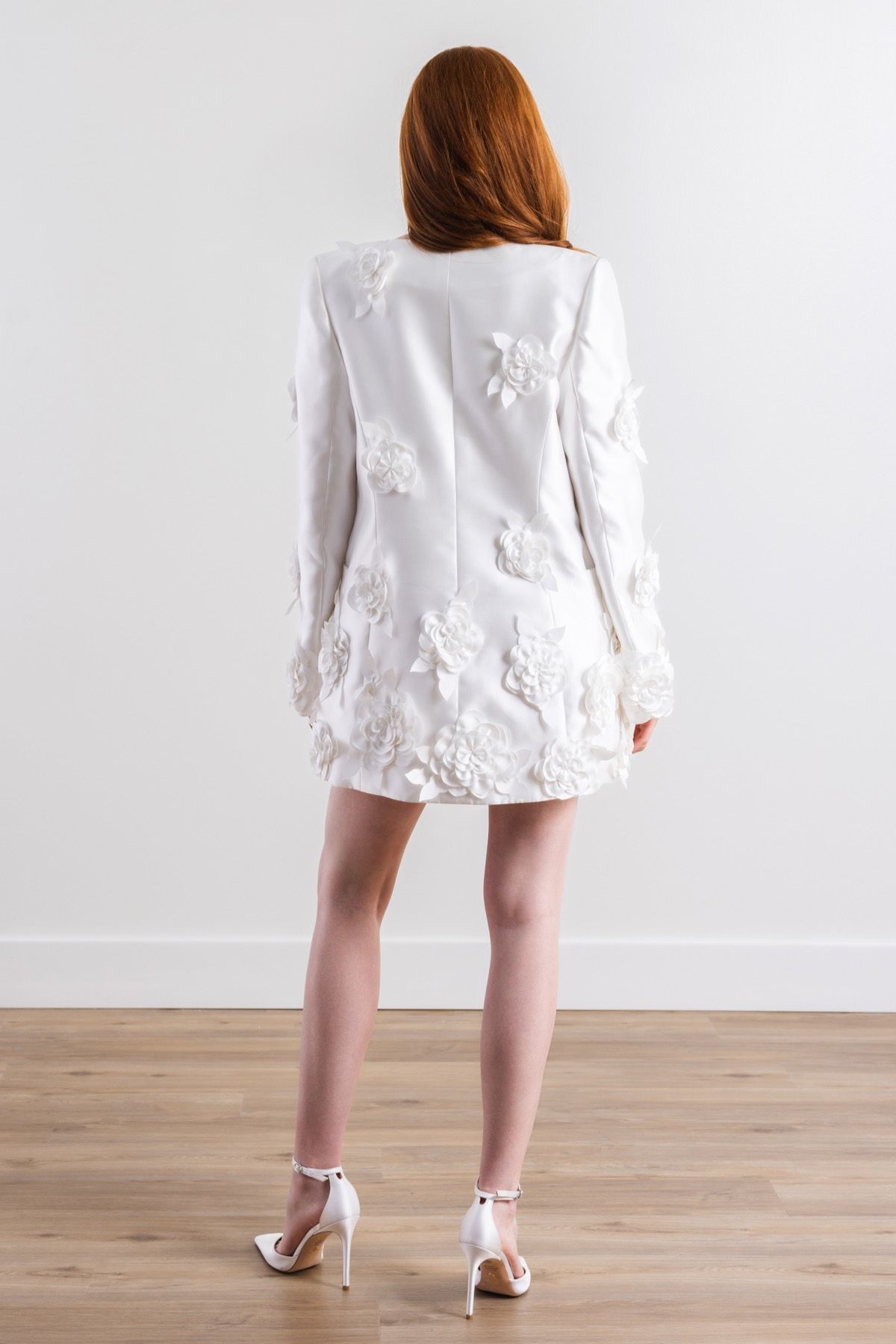 The back of a woman wearing a white dress and heels.