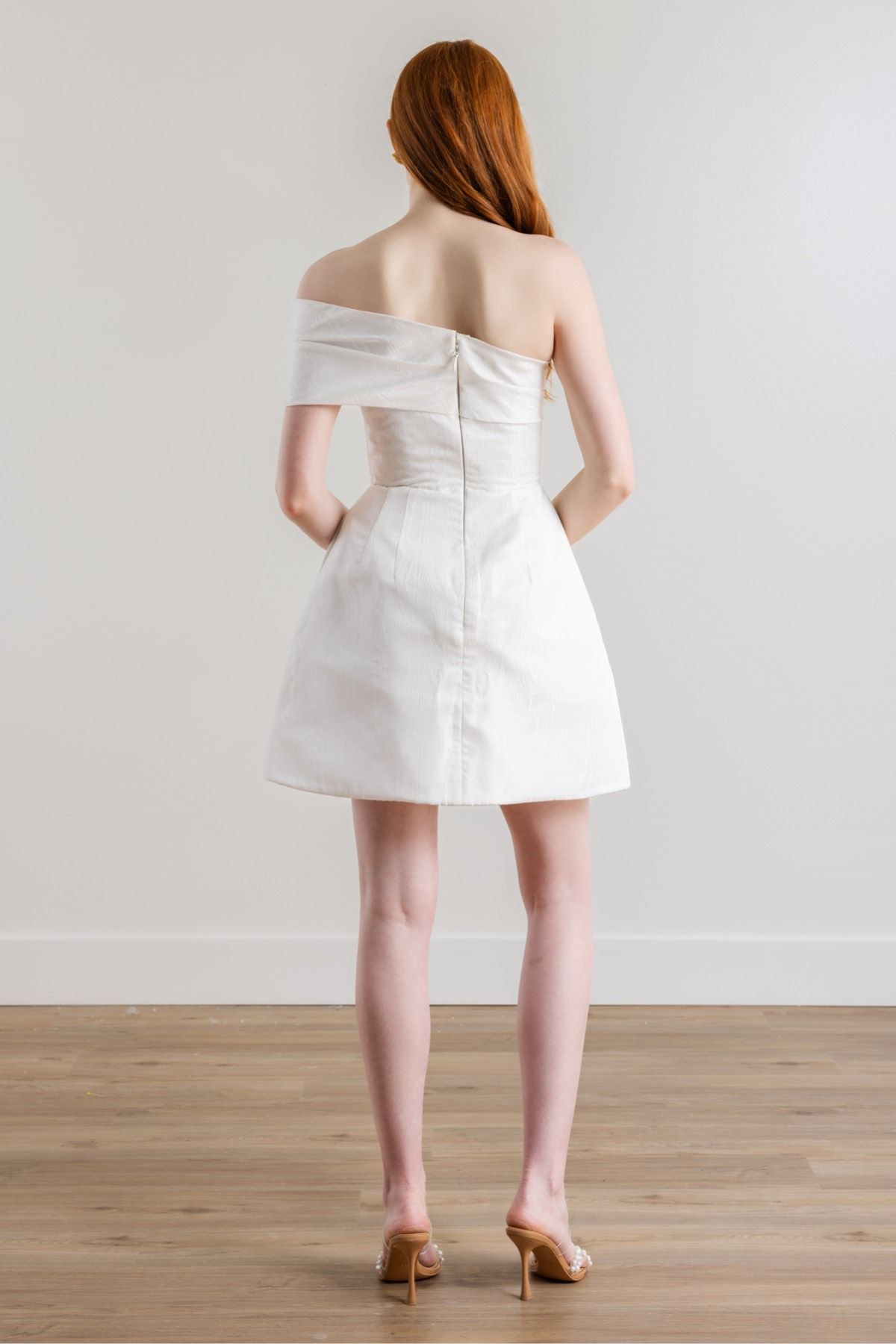 The back of a woman wearing a white off the shoulder dress.