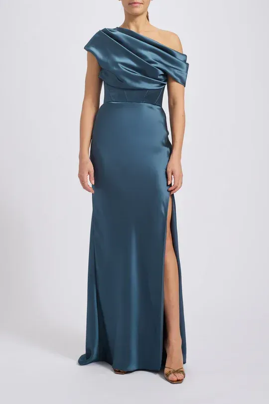 A woman is wearing a blue one shoulder dress with a high slit.