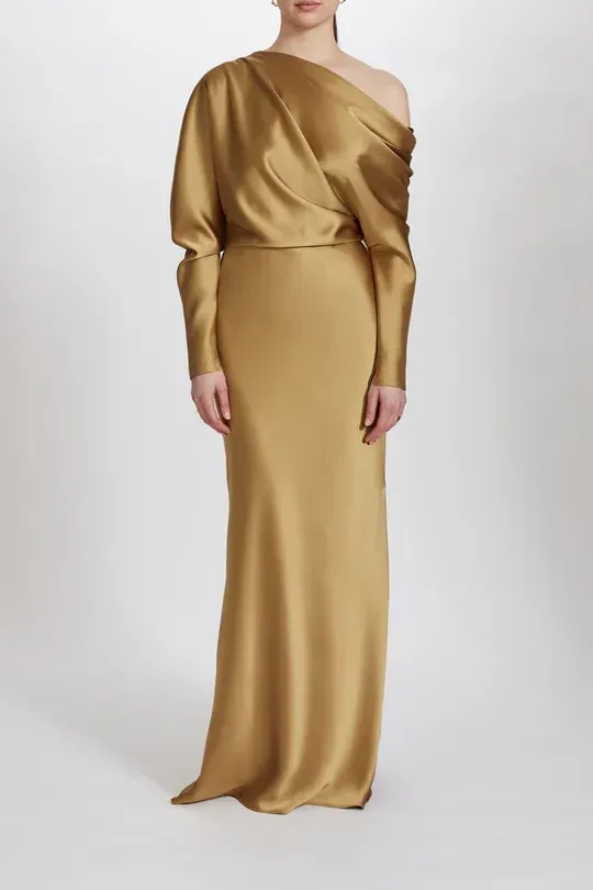 A woman is wearing a long gold dress with long sleeves.