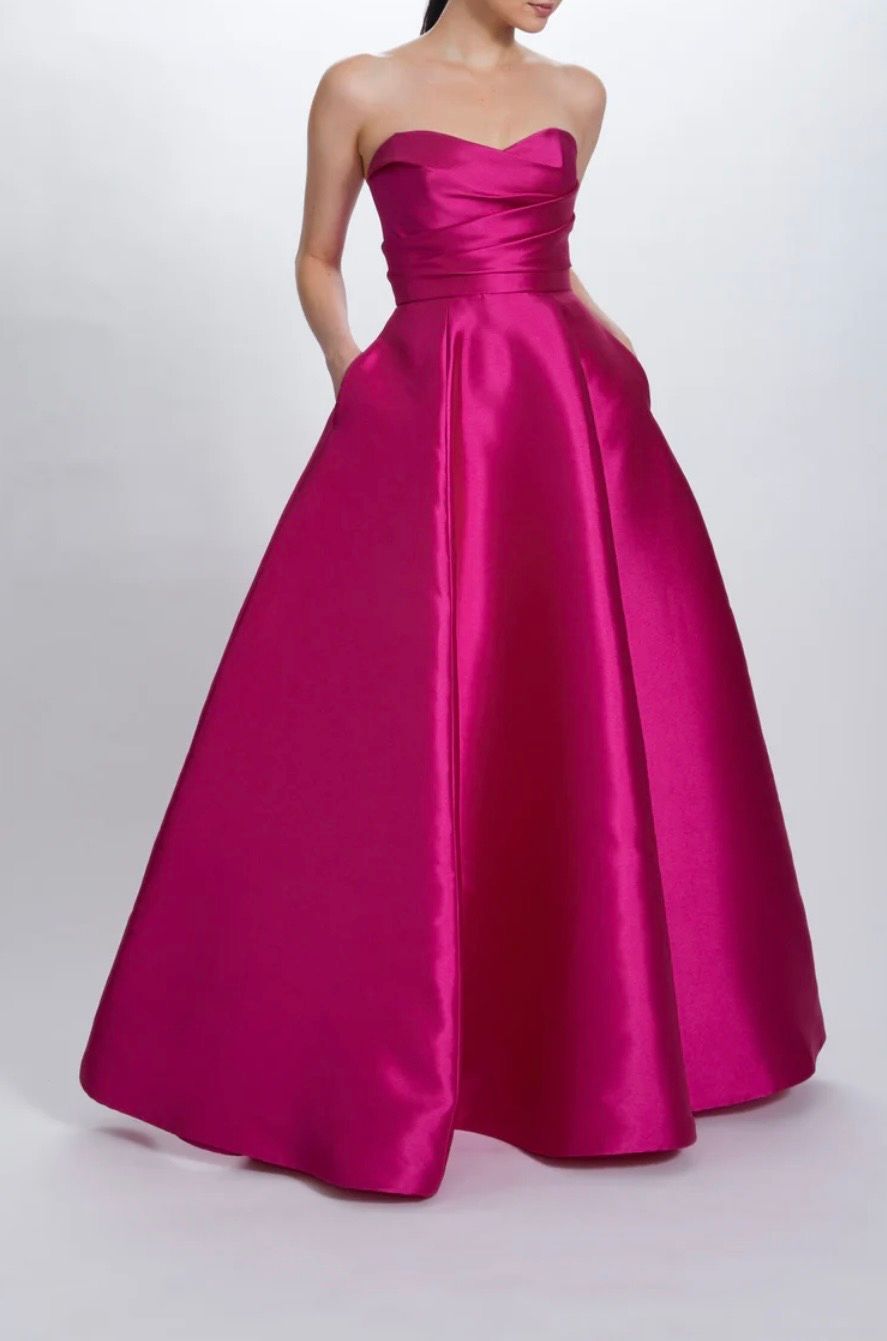 A woman is wearing a pink strapless dress with pockets