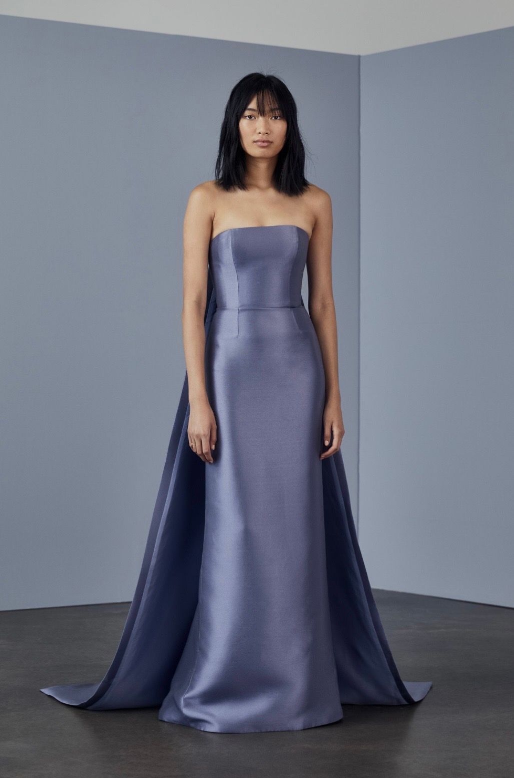 A woman is wearing a strapless blue dress with a long train.