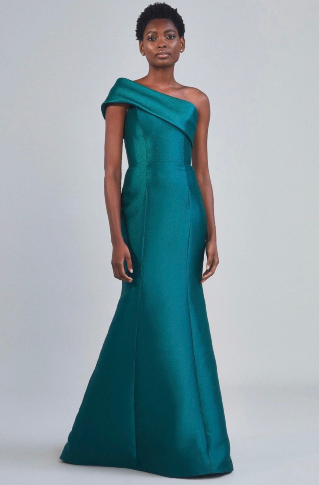 A woman is wearing a green one shoulder dress.