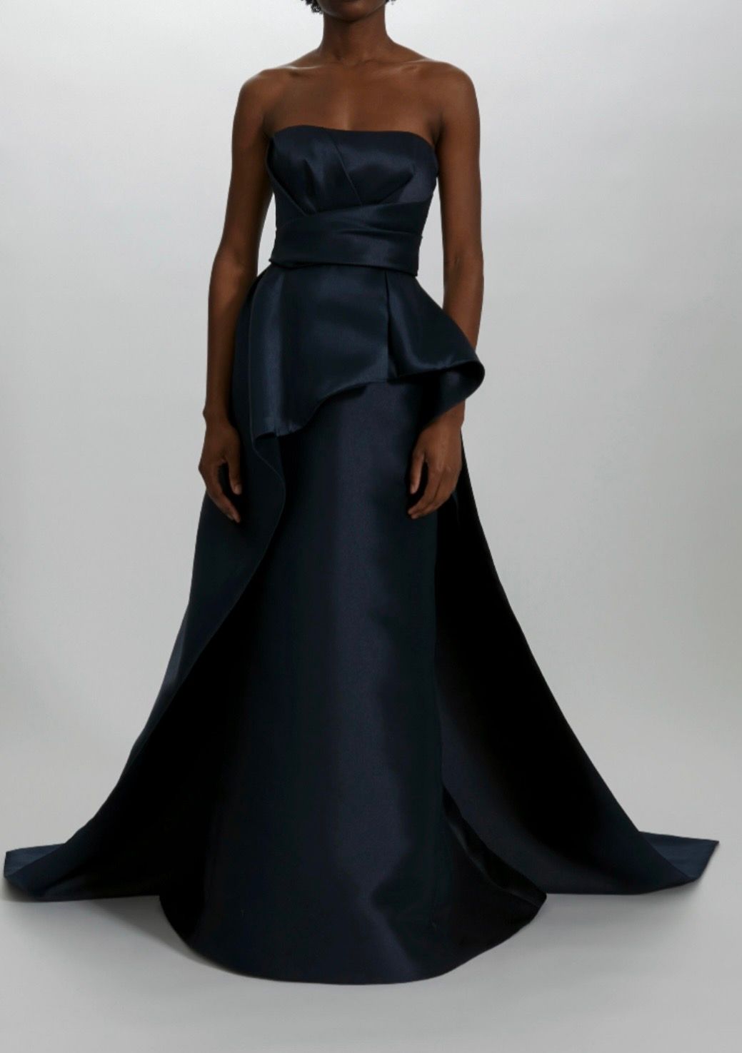 A woman is wearing a strapless black dress with a ruffled skirt