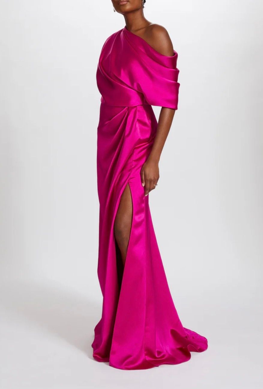 A woman is wearing a long pink dress with a high slit.
