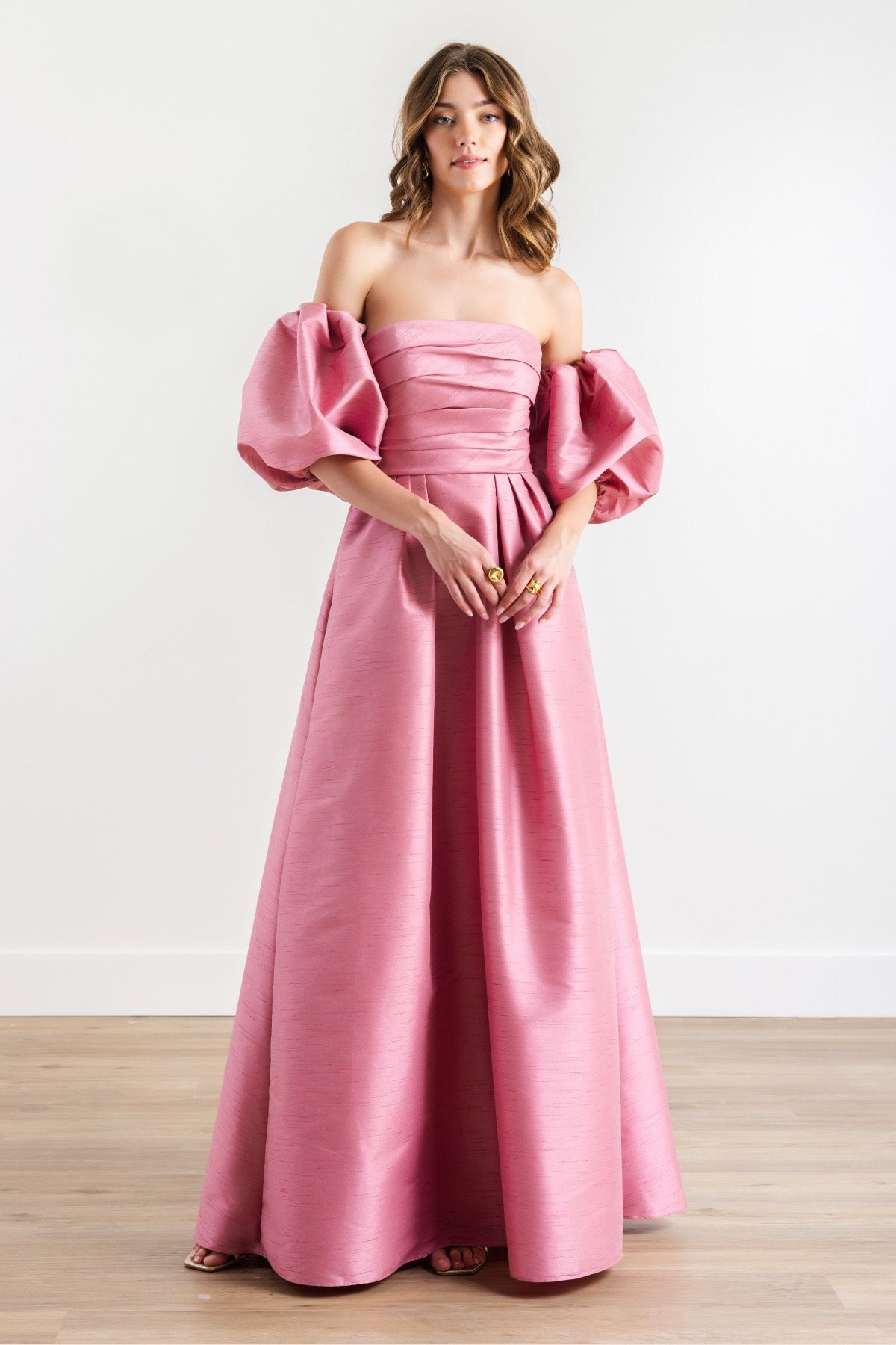 A woman is wearing a pink dress with puffed sleeves.
