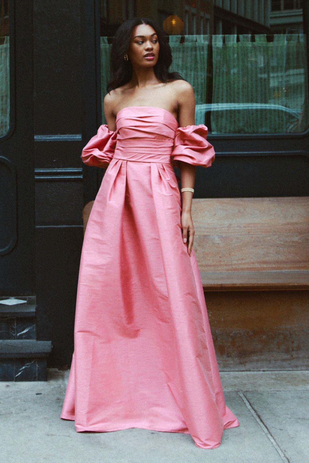 A woman is wearing a pink dress with puffed sleeves.